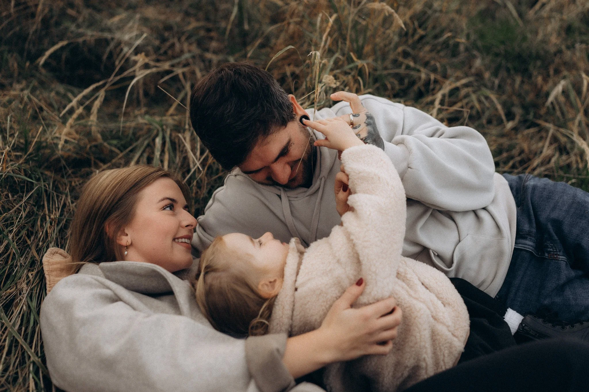 Maminka a tatínek objímají dceru při rodinném focení v přírodě
