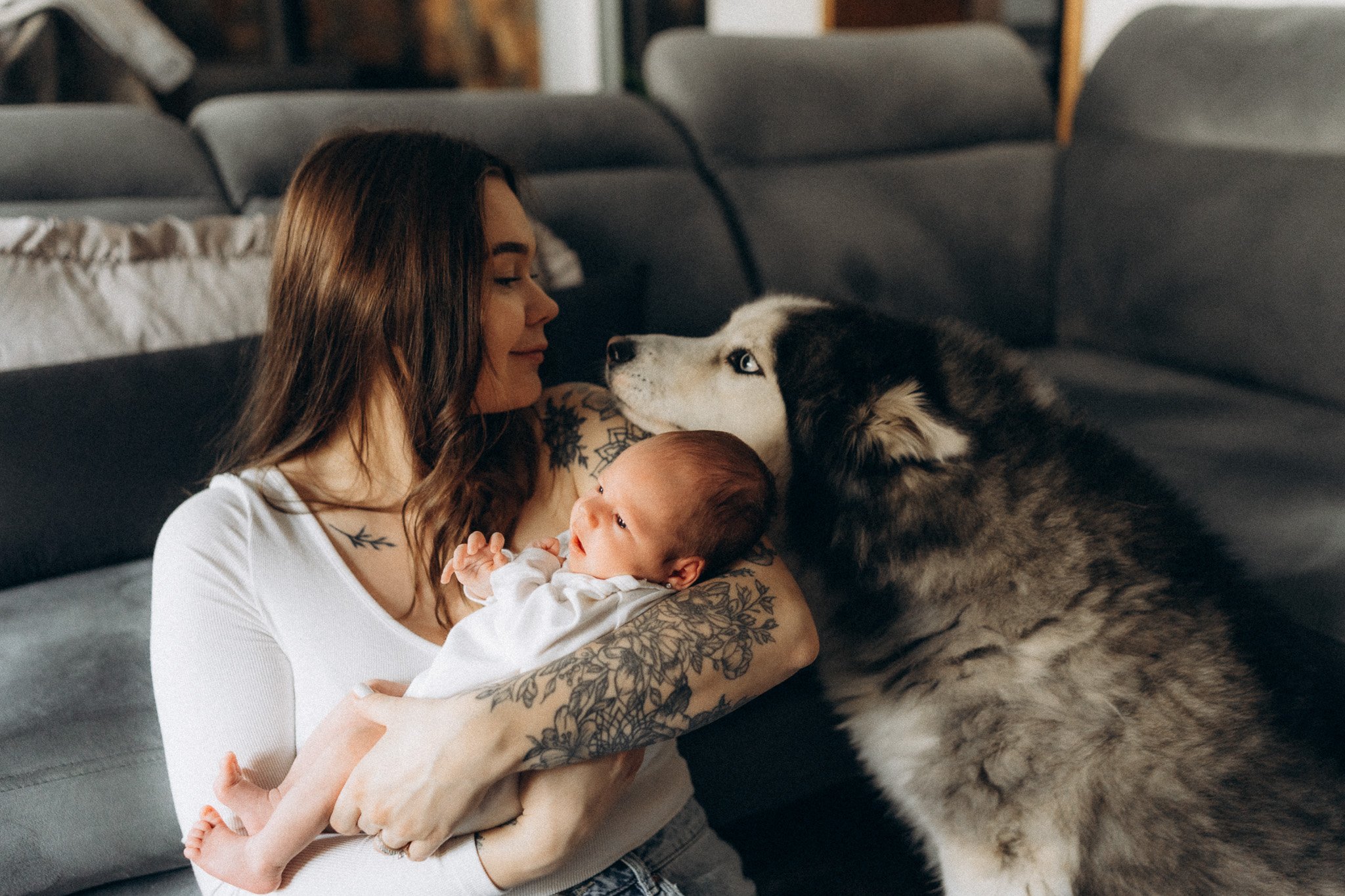 Maminka objímá miminko, zatímco pejsek sedí vedle nich