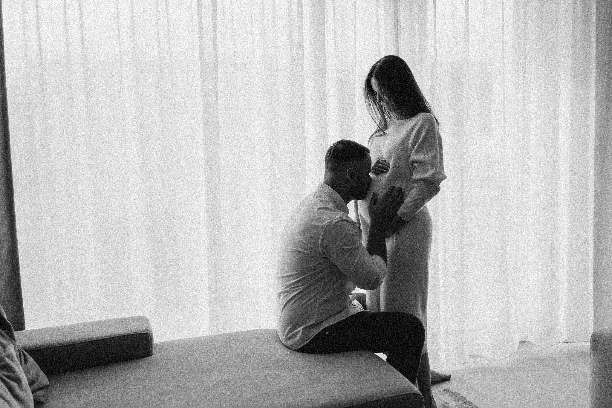 Partner se sklání k těhotenskému bříšku při focení