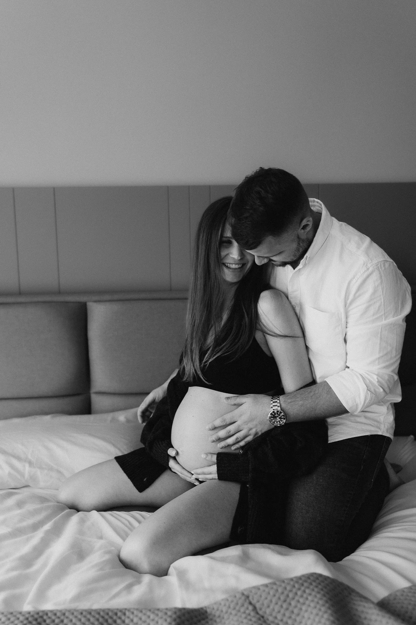 Partner objímá těhotnou ženu při focení v bytě