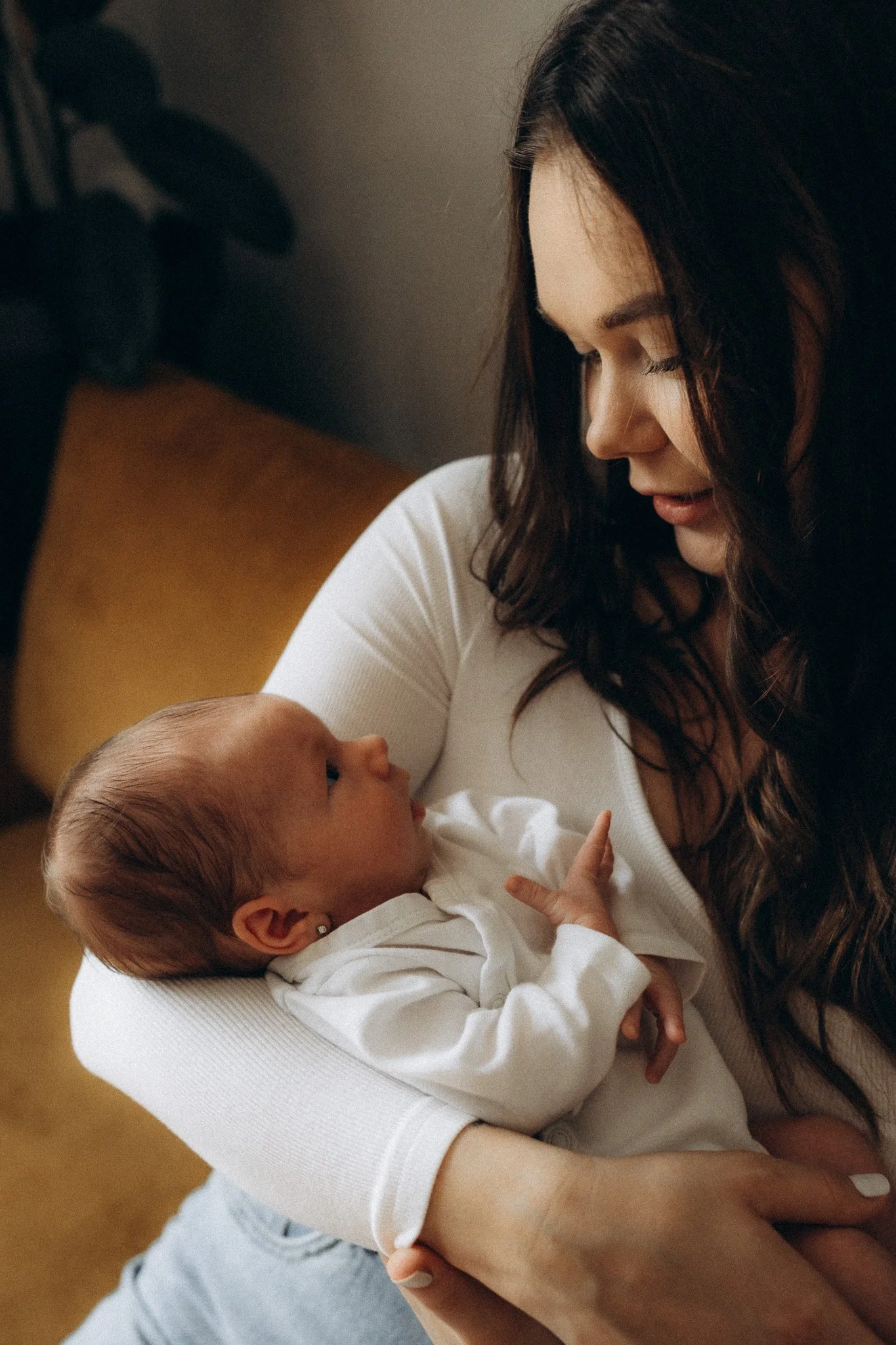 Maminka drží novorozené miminko při focení doma