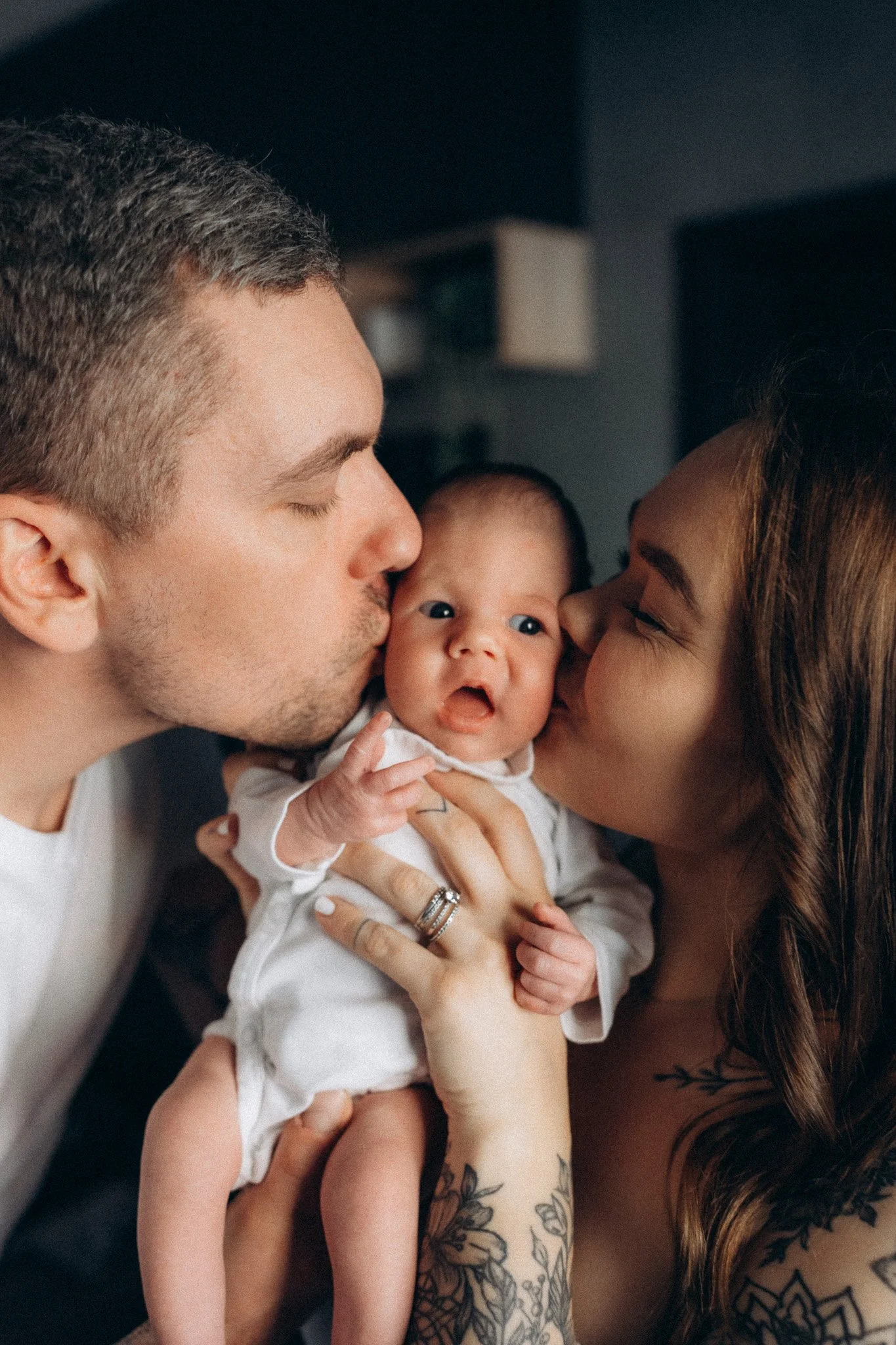 Rodiče dávají novorozenému dítěti pusu v domácím prostředí