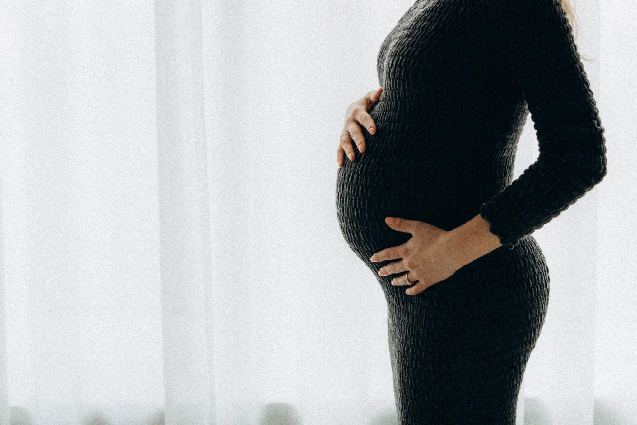 Detail siluety těhotenského bříška proti světlu