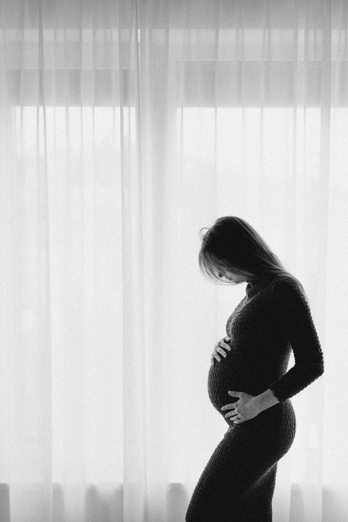 Silueta těhotné ženy v proti světlu u okna