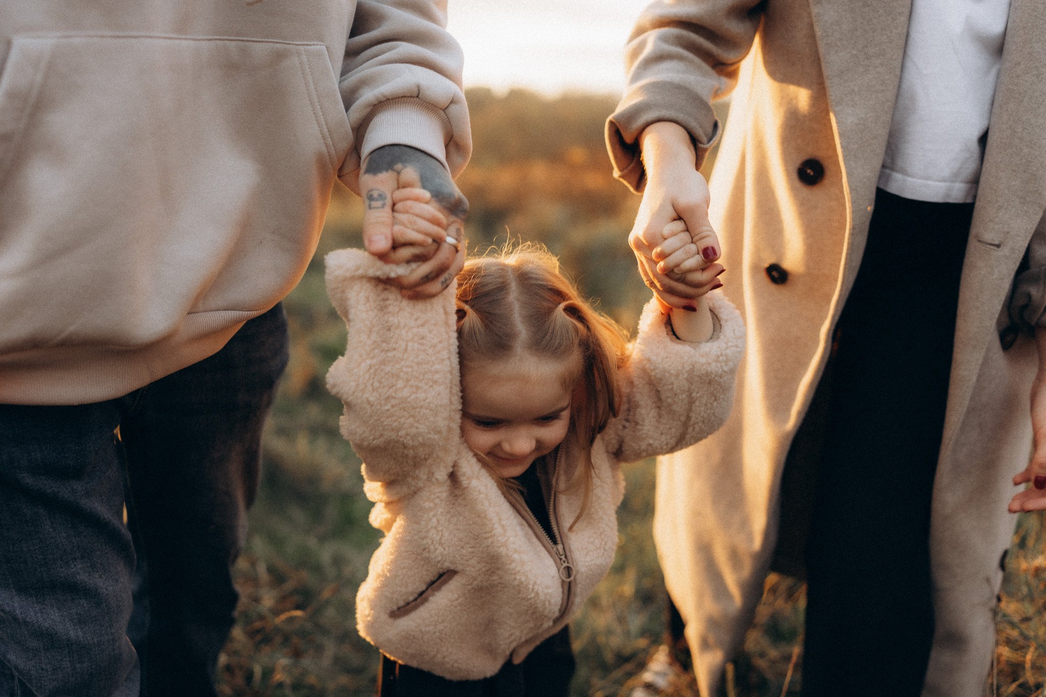 Maminka a tatínek drží dceru při focení v přírodě