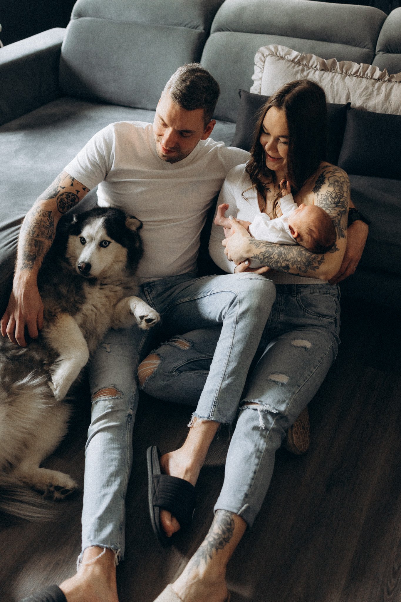 Novorozené miminko v náručí rodičů s pejskem v domácím prostředí
