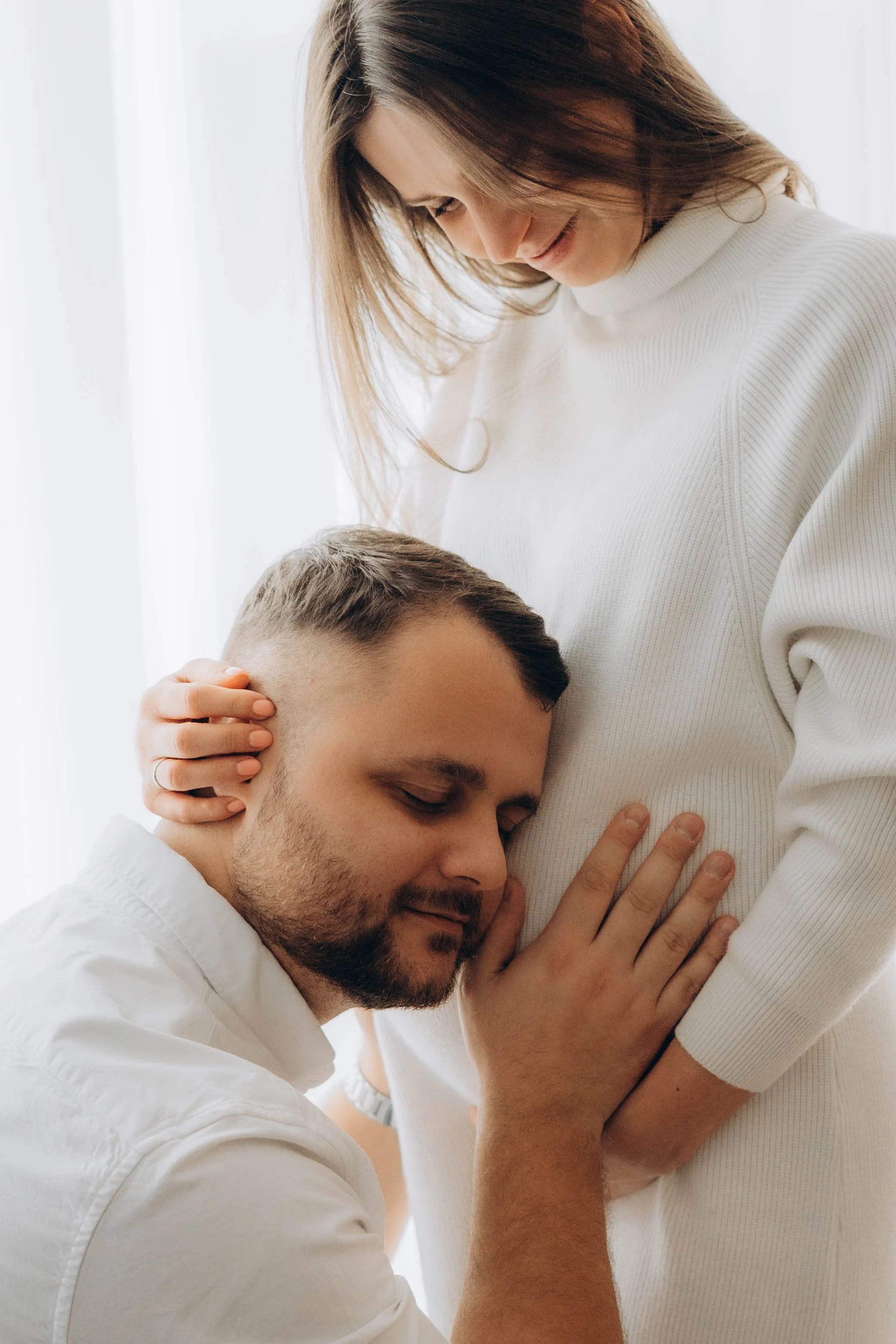 Detail rukou a hlavy partnera na těhotenském bříšku