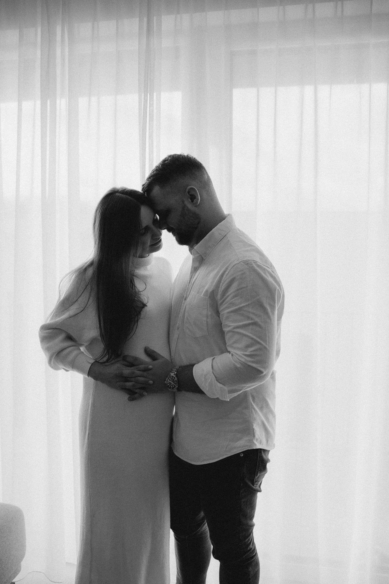 Těhotenský portrét páru v minimalistickém prostoru