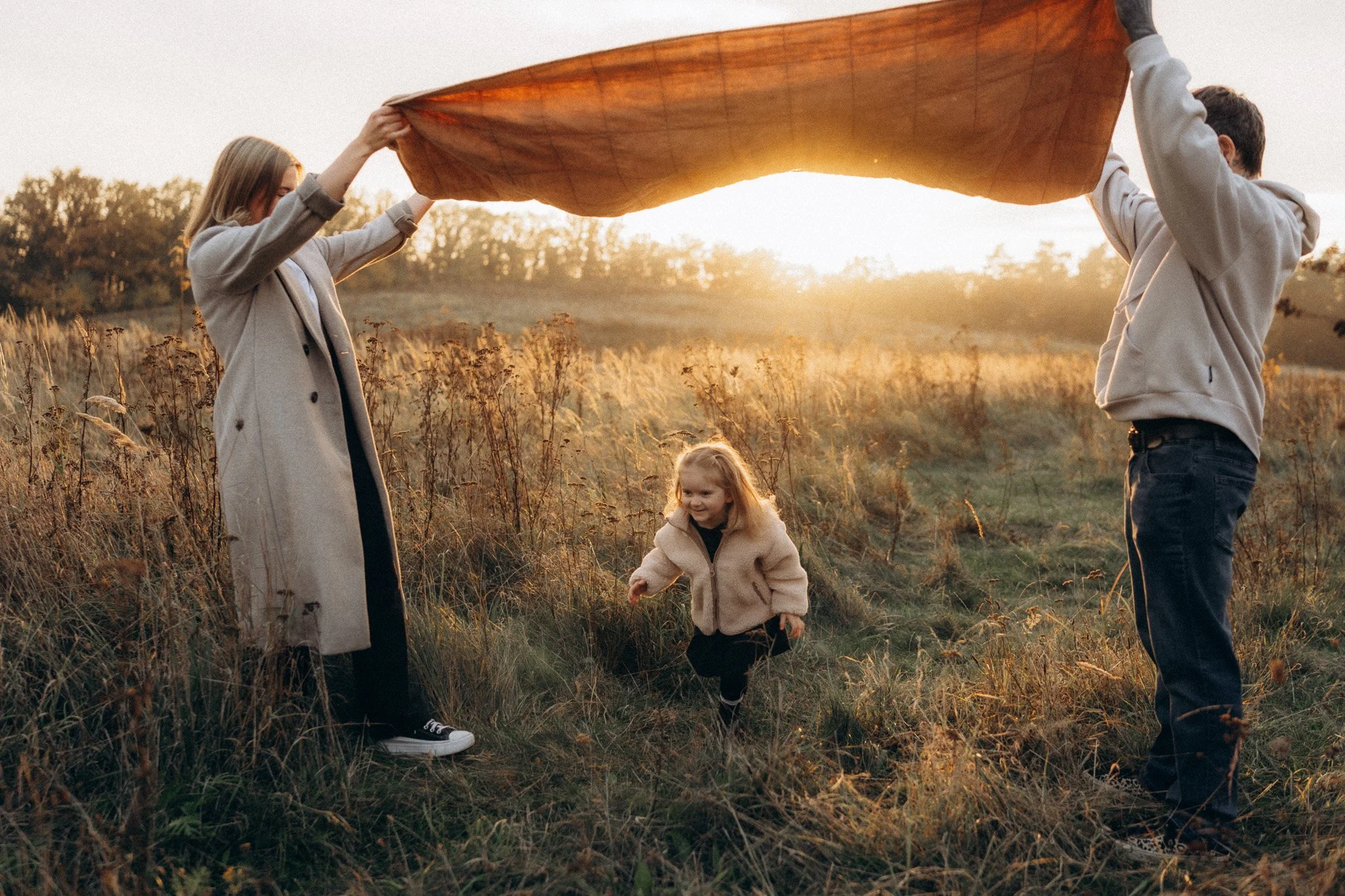 Maminka, tatínek a dcera při přirozeném rodinném focení v podvečerním světle
