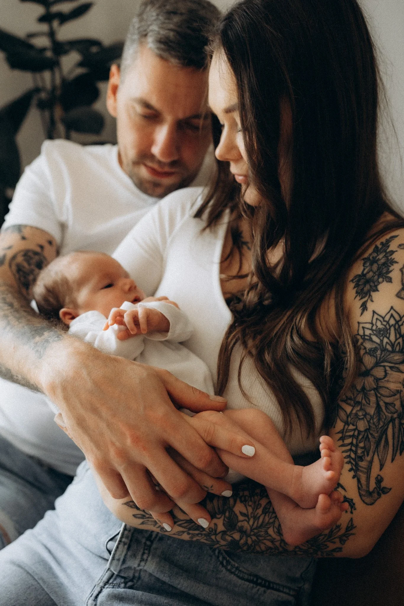 Rodiče společně drží novorozené dítě v obývacím pokoji