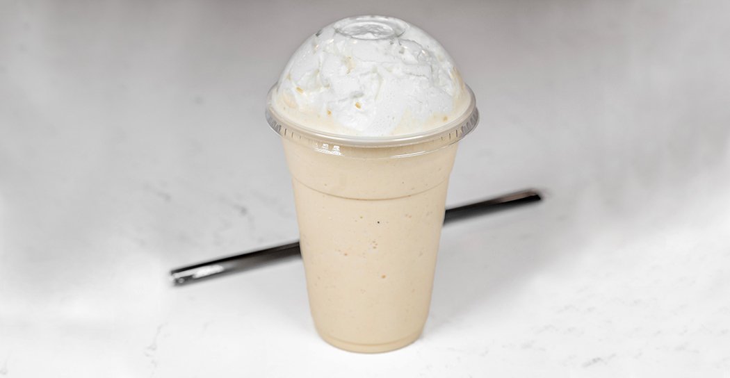 Milkshake with whipped cream in a plastic cup on a white background.