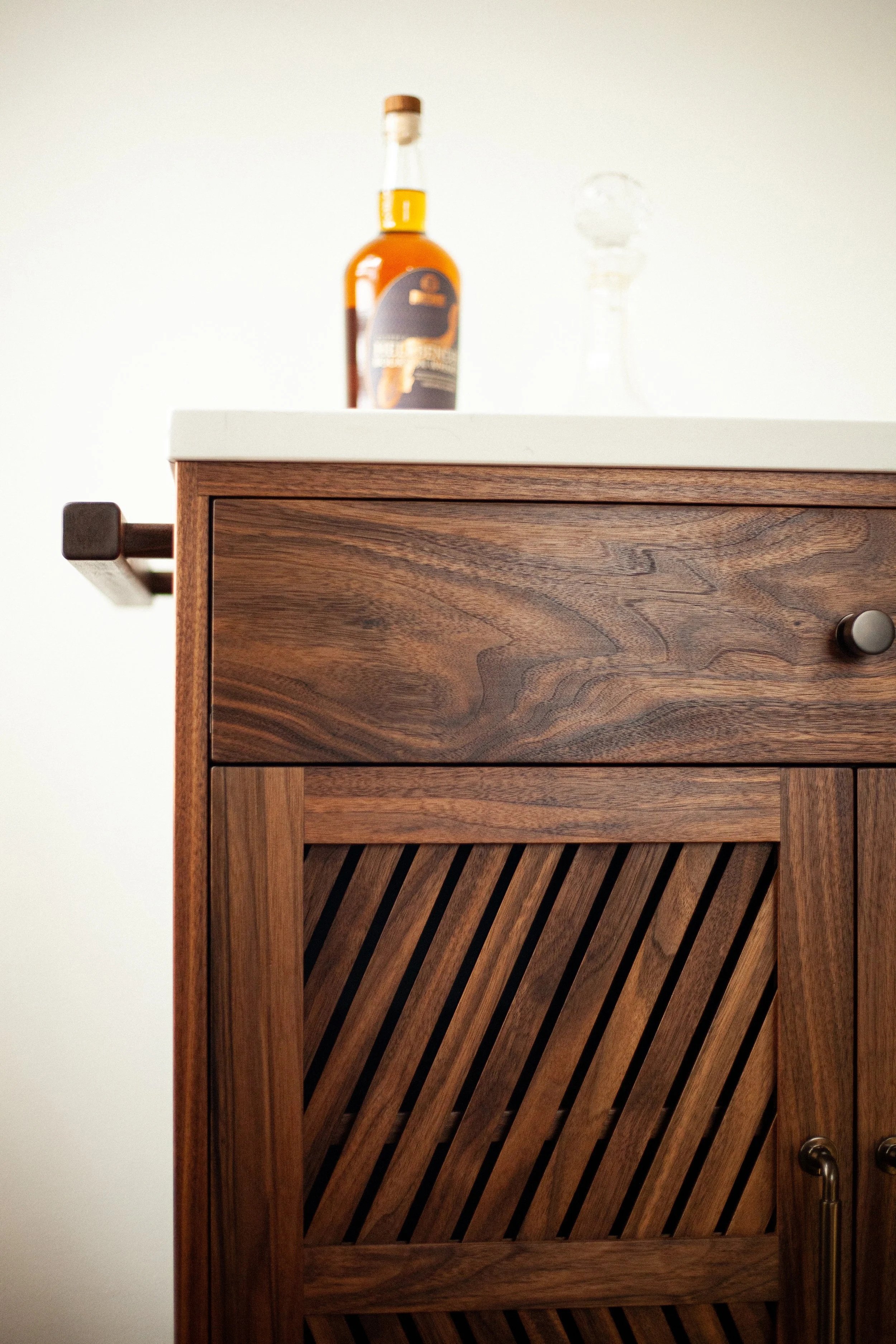 walnut bar cart with inset doors featuring a herringbone slat construction, dark bronze hardware, and a quartz countertop