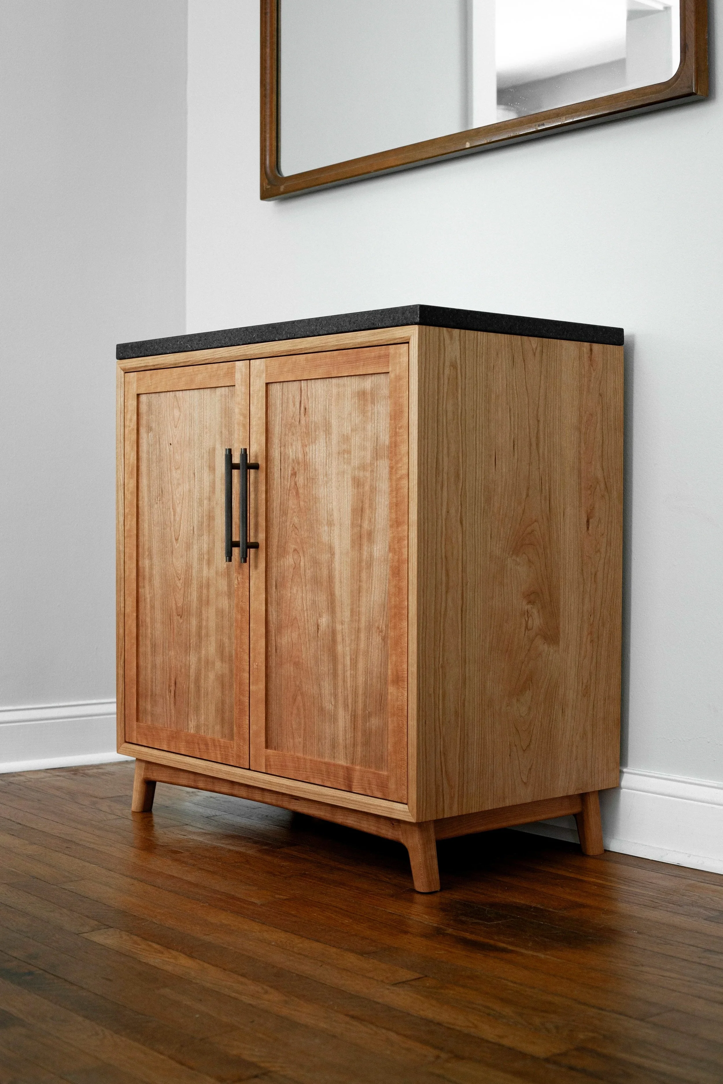 cherry bar cabinet with dark granite countertop, inset shaker doors, and dark bronze hardware