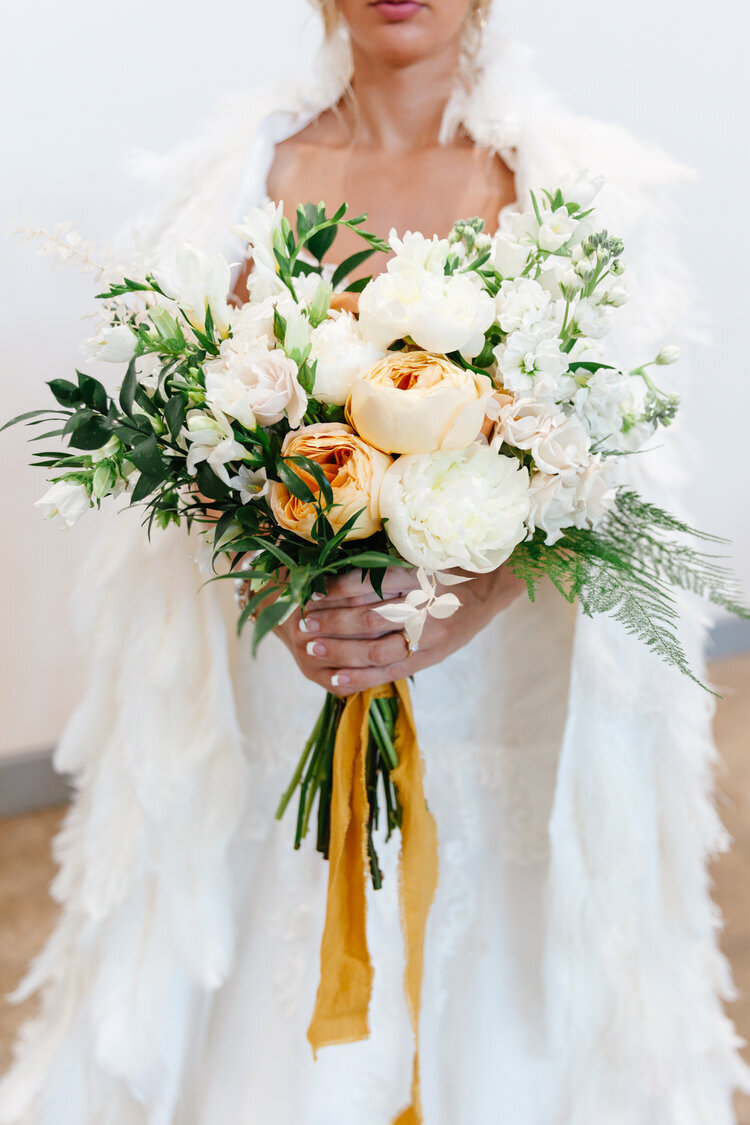 Bridal+wedding+gown+with+feather+cape+and+large+bouquet+of+orange+florals.jpg