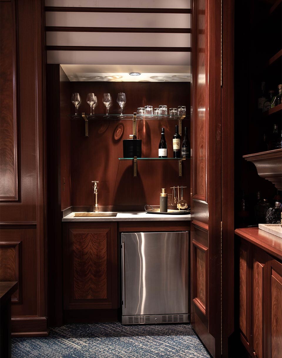 Hidden bar cabinet with custom glass floating shelves and brass brackets used in executive office Cleveland Ohio