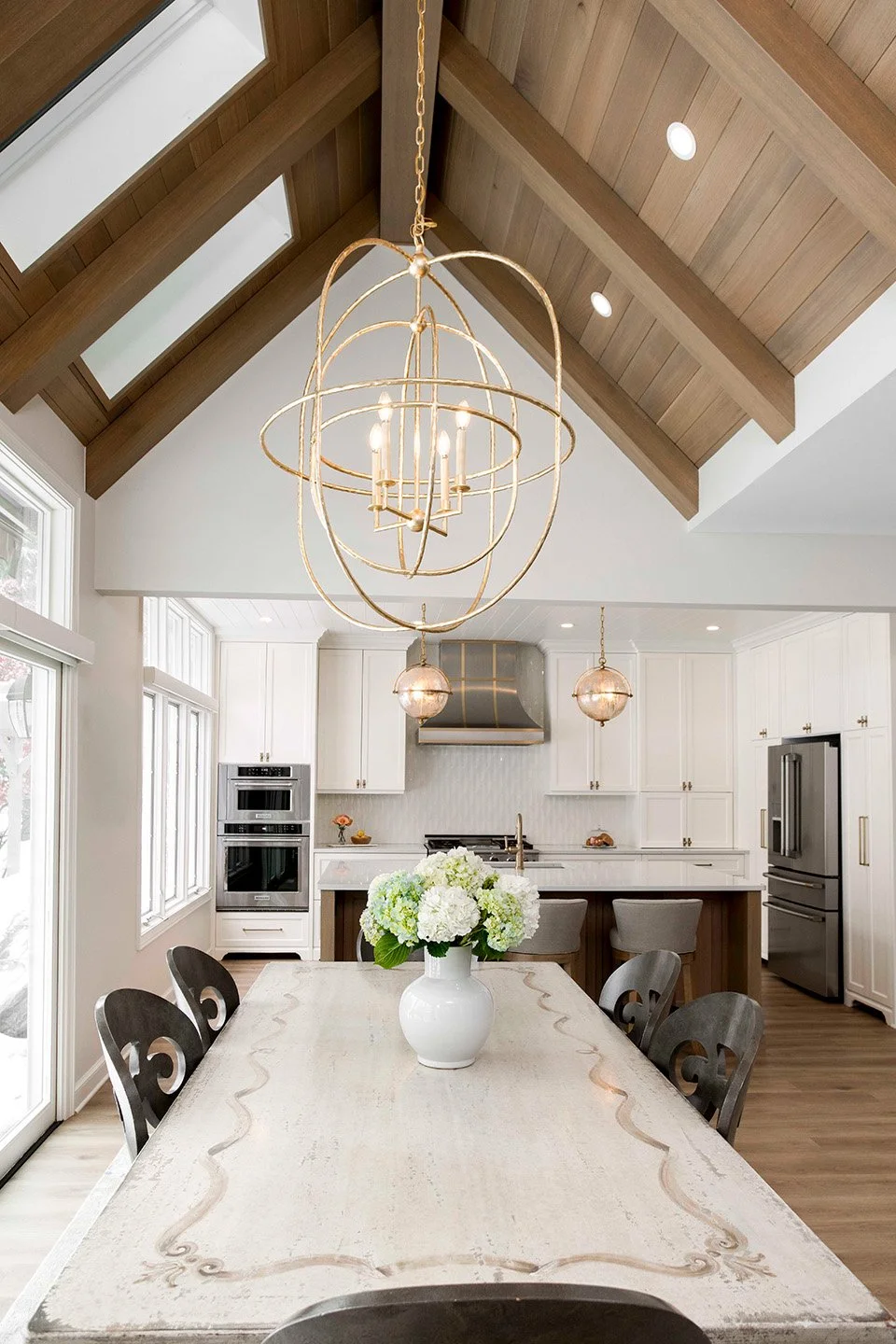 Bright breakfast nook with a vaulted shiplap ceiling, wood beam detail, pendant lighting, a marble-topped table, and views into the kitchen | Ducy Design