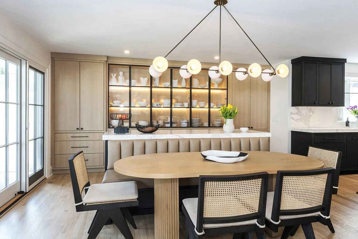 Dining nook with wood and cane chairs, a linear chandelier, large windows, and warm natural light in a modern traditional home | Ducy Design