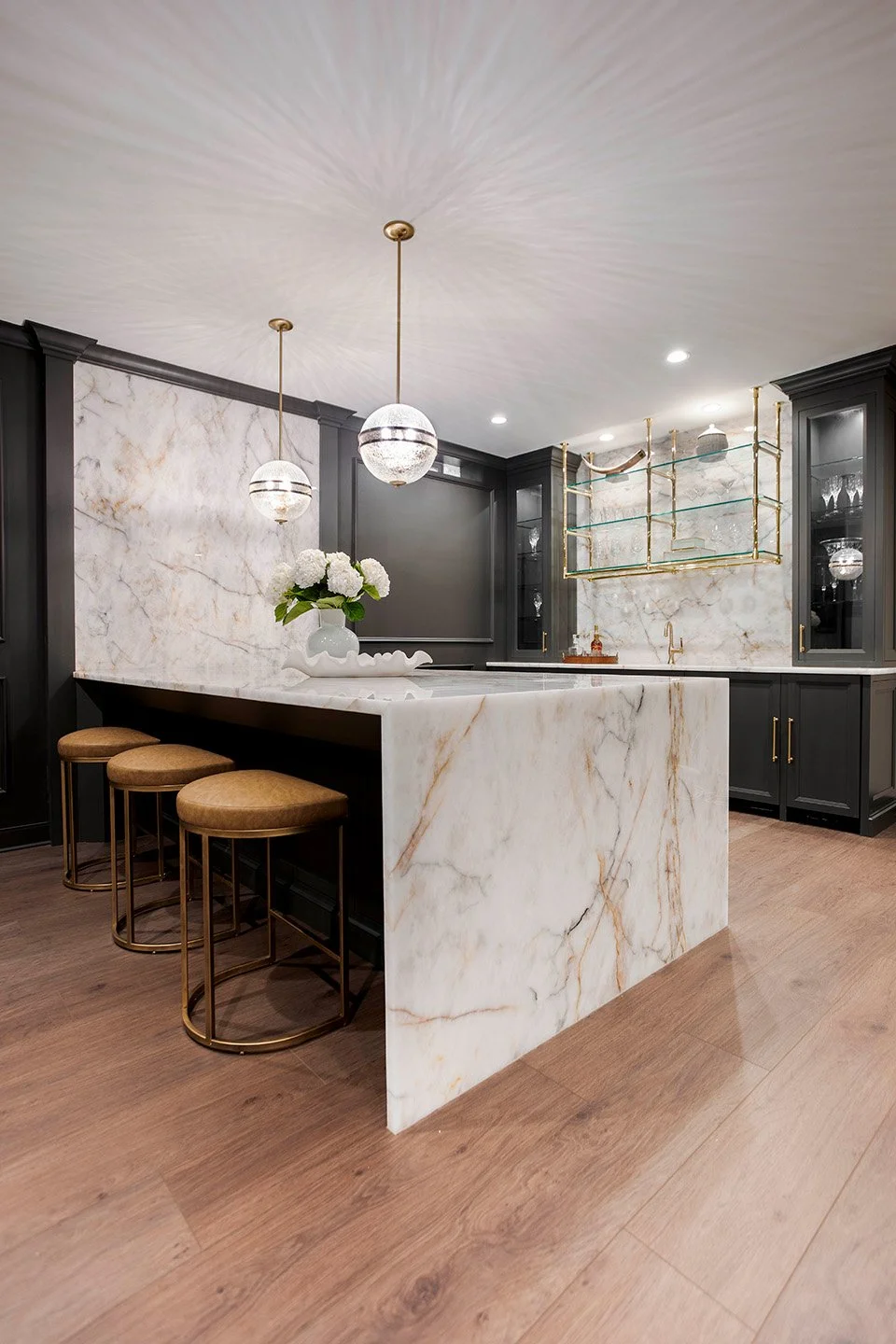 Close-up of a Crystal Thunder quartzite bar island with a dramatic waterfall edge, bold veining, and a sleek black base in the Luxe Lounge | Ducy Design