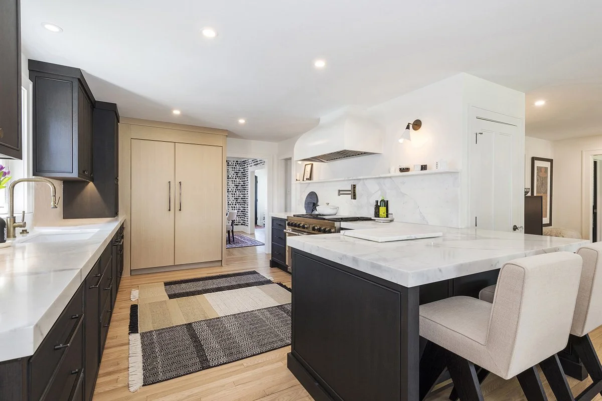 Close-up of a kitchen with a dark painted island, warm wood cabinetry, and high-contrast finishes in a modern traditionalist style | Ducy Design