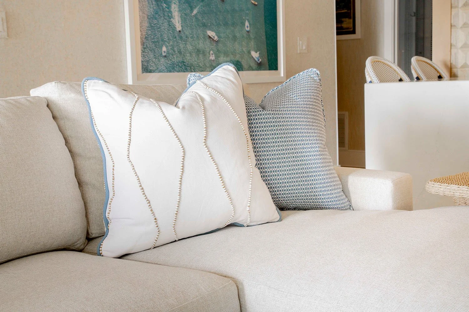 Close-up of a neutral linen sofa styled with white and blue accent pillows in a soft, layered lakehouse living room palette | Ducy Design