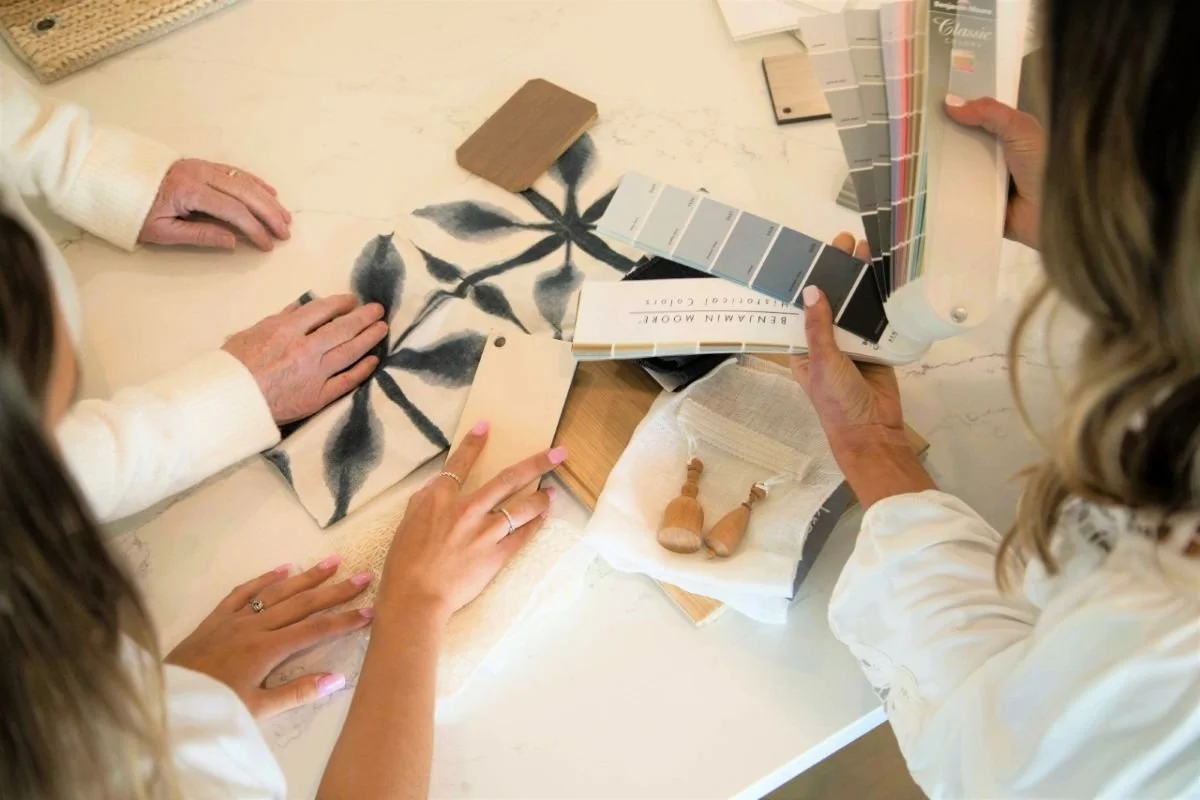 Two people reviewing interior finish samples, paint swatches, and tile selections during a design consultation at Ducy Design