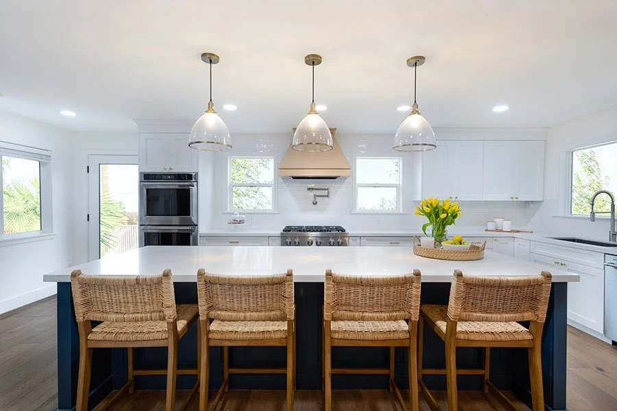 Coastal farmhouse kitchen with custom wood range hood quartz countertops white subway tile backsplash and navy blue island Phoenix Arizona