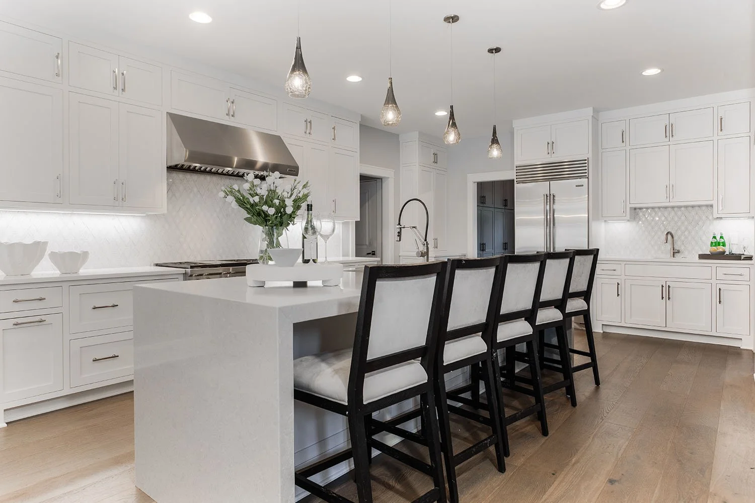 Cleveland Ohio kitchen with inset white shaker cabinetry and second-row upper cabinets, and large island with a waterfall quartz countertop