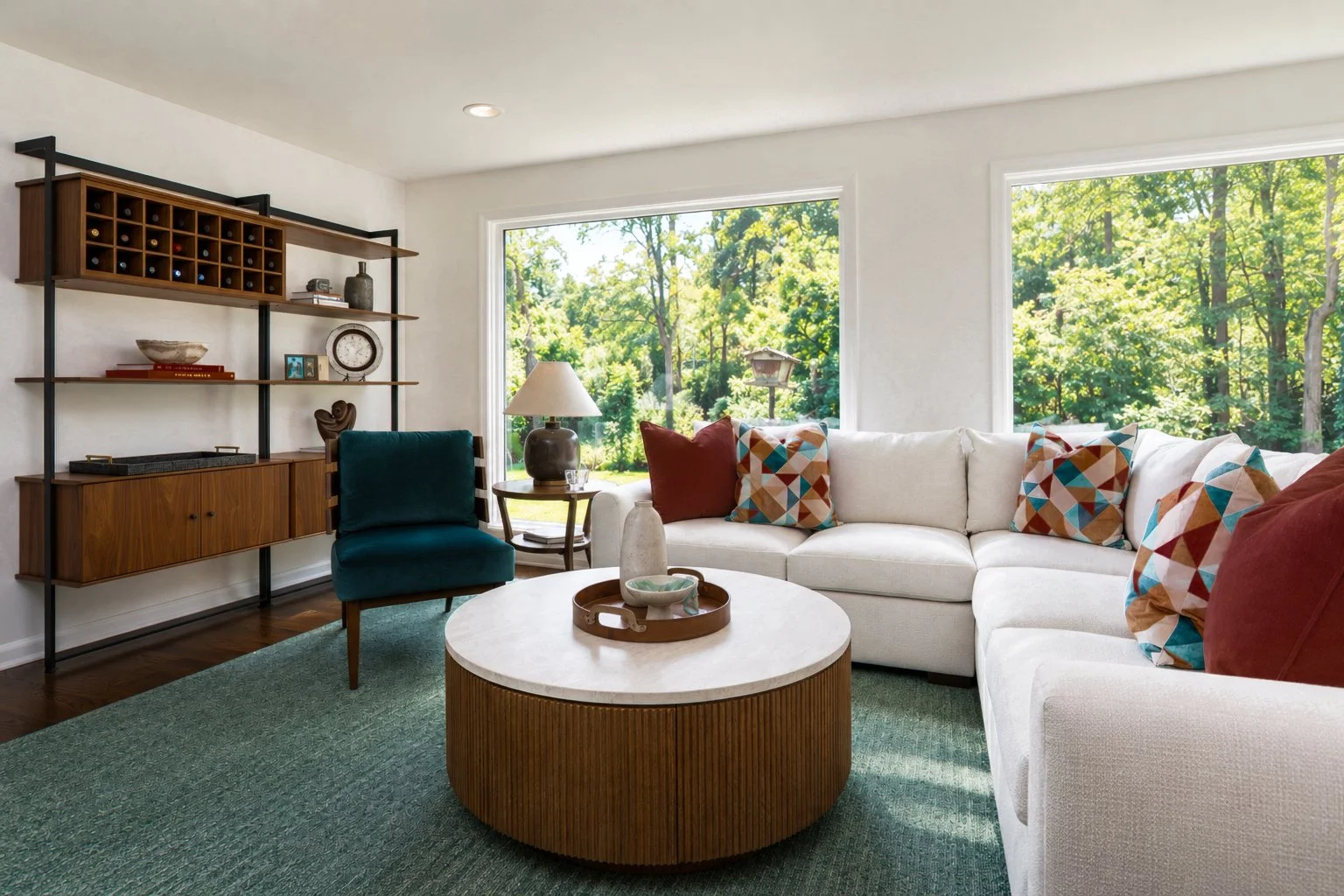 Mid-century modern living room in Cleveland featuring a white sectional sofa, colorful accent pillows, teal lounge chair, and round wood coffee table.