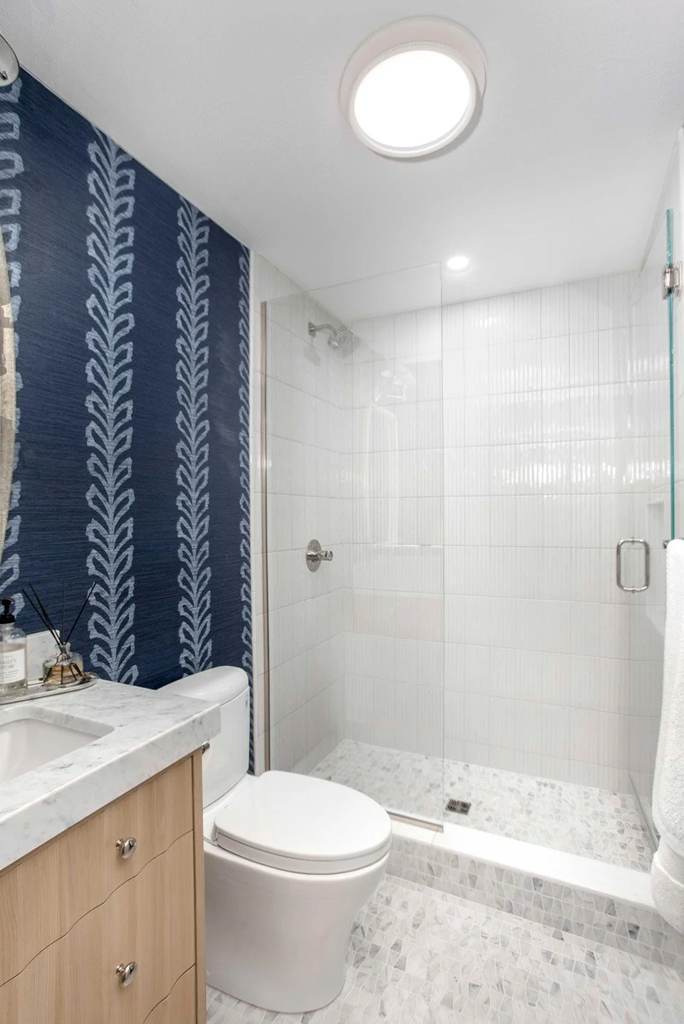 Walk-in shower with white subway tile walls, a bold navy blue tile accent panel, and clean chrome fixtures in the Polished Lakehouse | Ducy Design