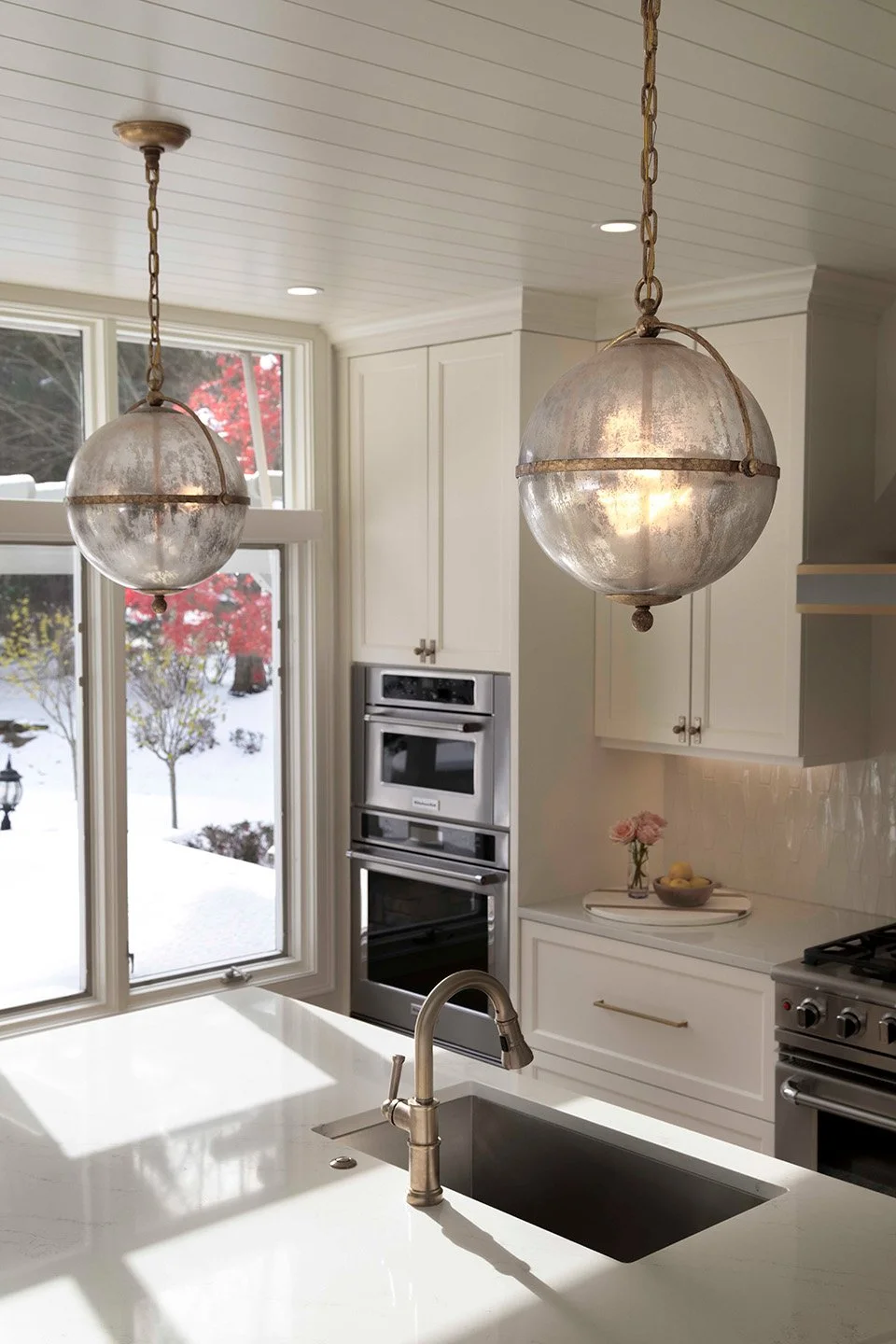 Detail view of kitchen bar seating with upholstered stools, warm wood cabinetry, and aged brass hardware in a refined entertaining kitchen | Ducy Design