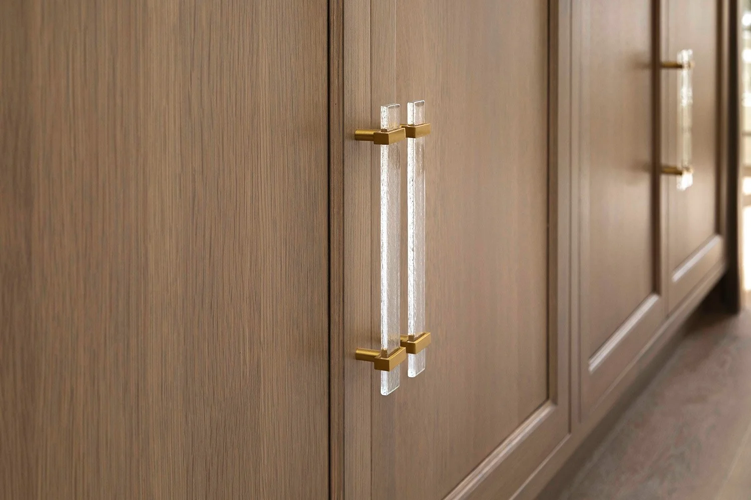 Close-up of warm oak cabinet doors with long brushed gold bar pulls, showcasing the refined material and hardware selections of The Entertainer's Haven | Ducy Design