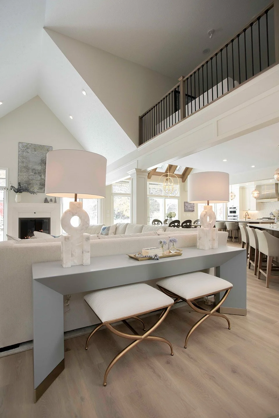 Wide shot of an open kitchen and dining area with warm wood tones, a large island, upholstered seating, and layered pendant lighting | Ducy Design
