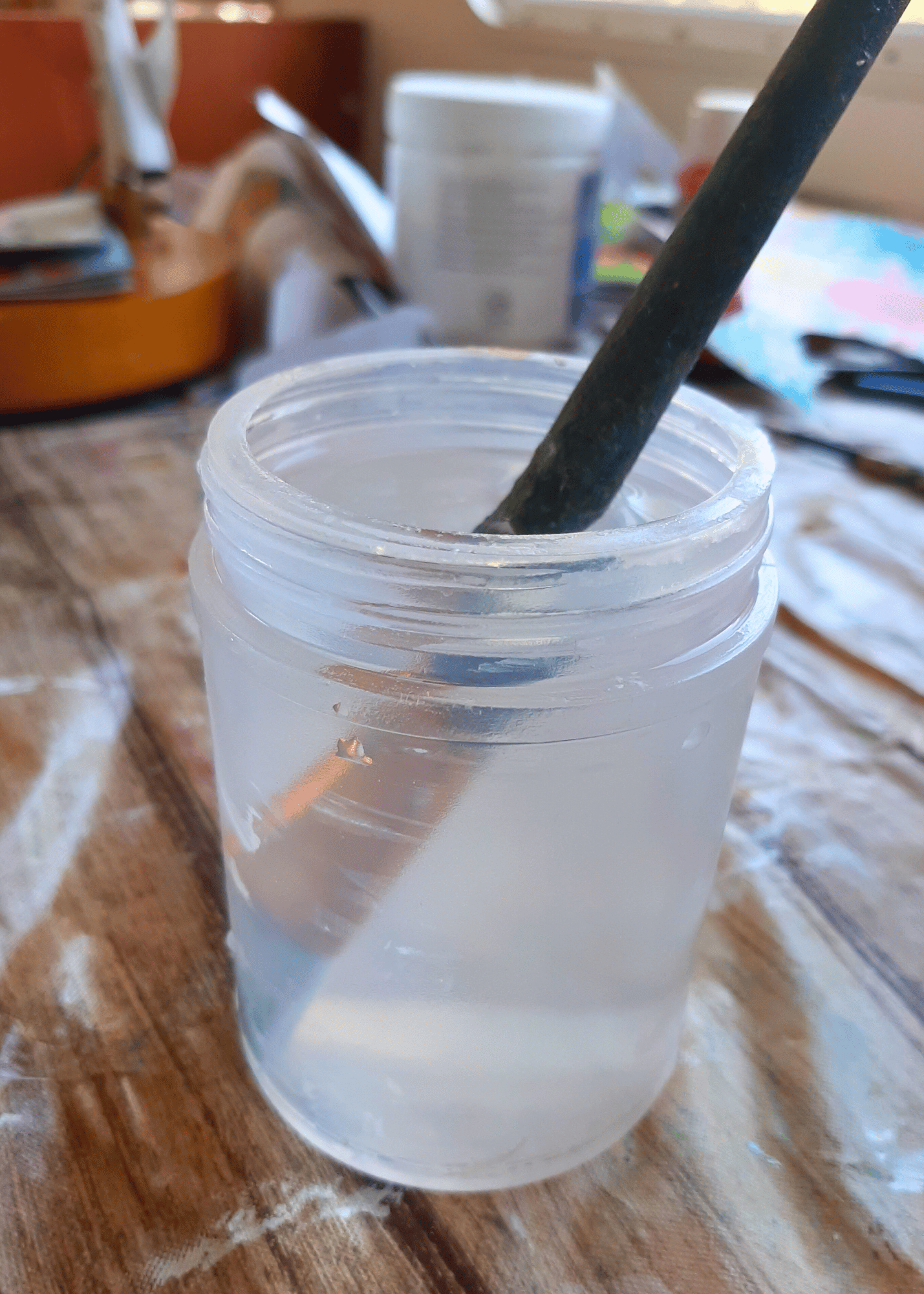 paint-brush-in-a-cup-of-water-on-table