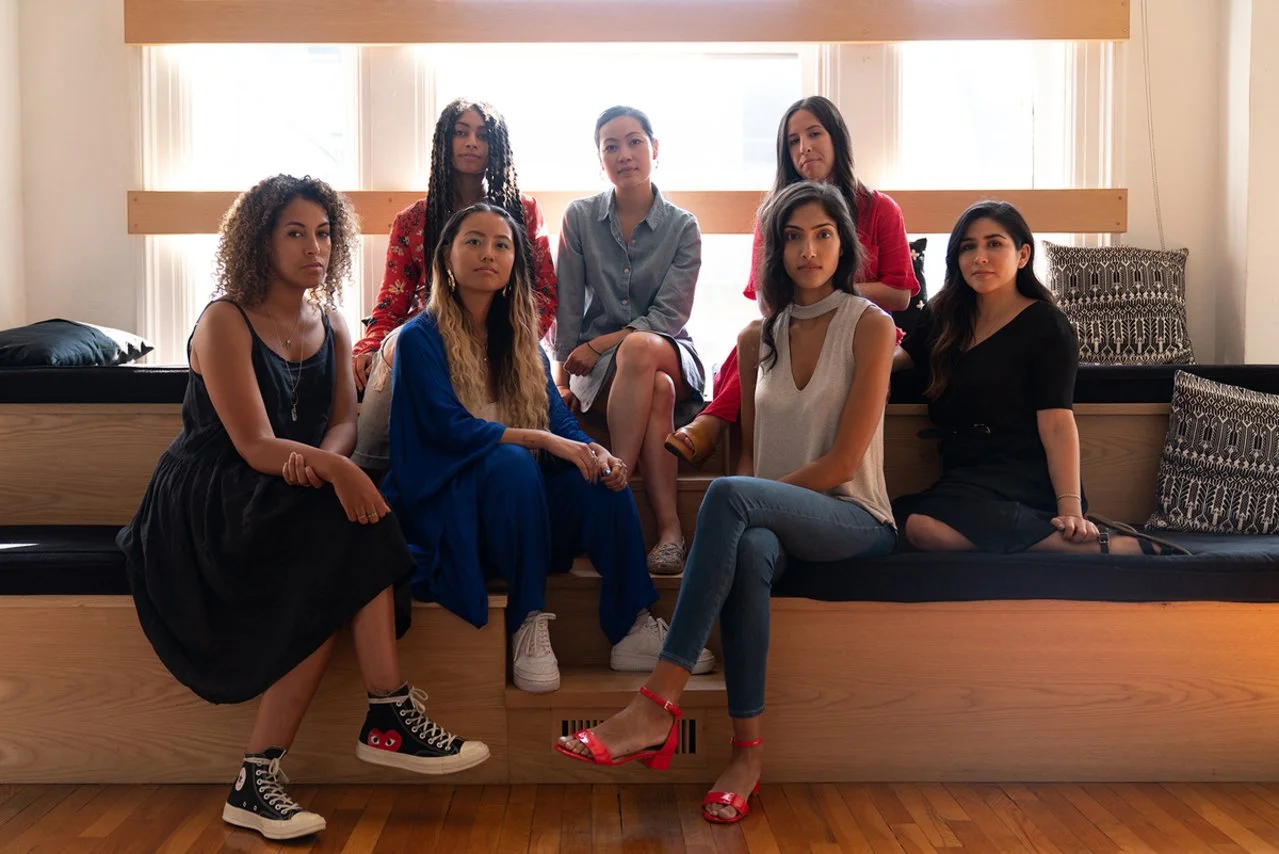 a multicultural group of women sit boldly and confidently inside an advertising agency library