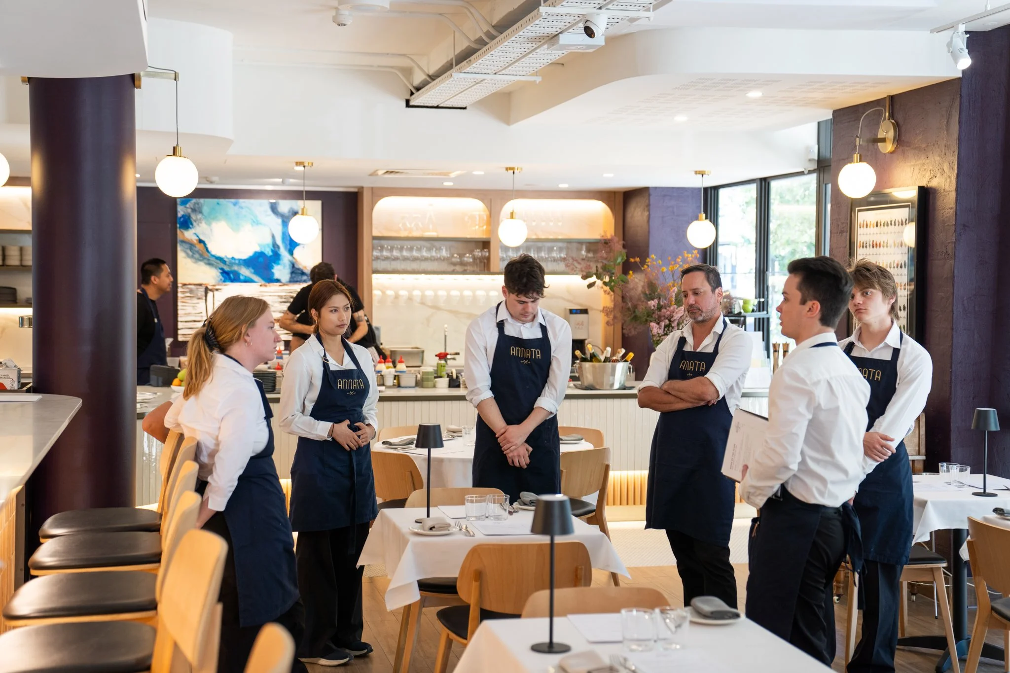 Annata Restaurant service team gathered for a pre-service briefing in the dining room