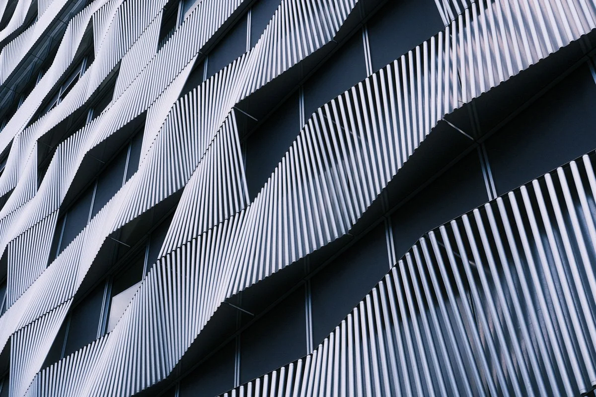 Abstract architectural photograph of flowing structural lines and repeating forms, evoking systems and structure.
