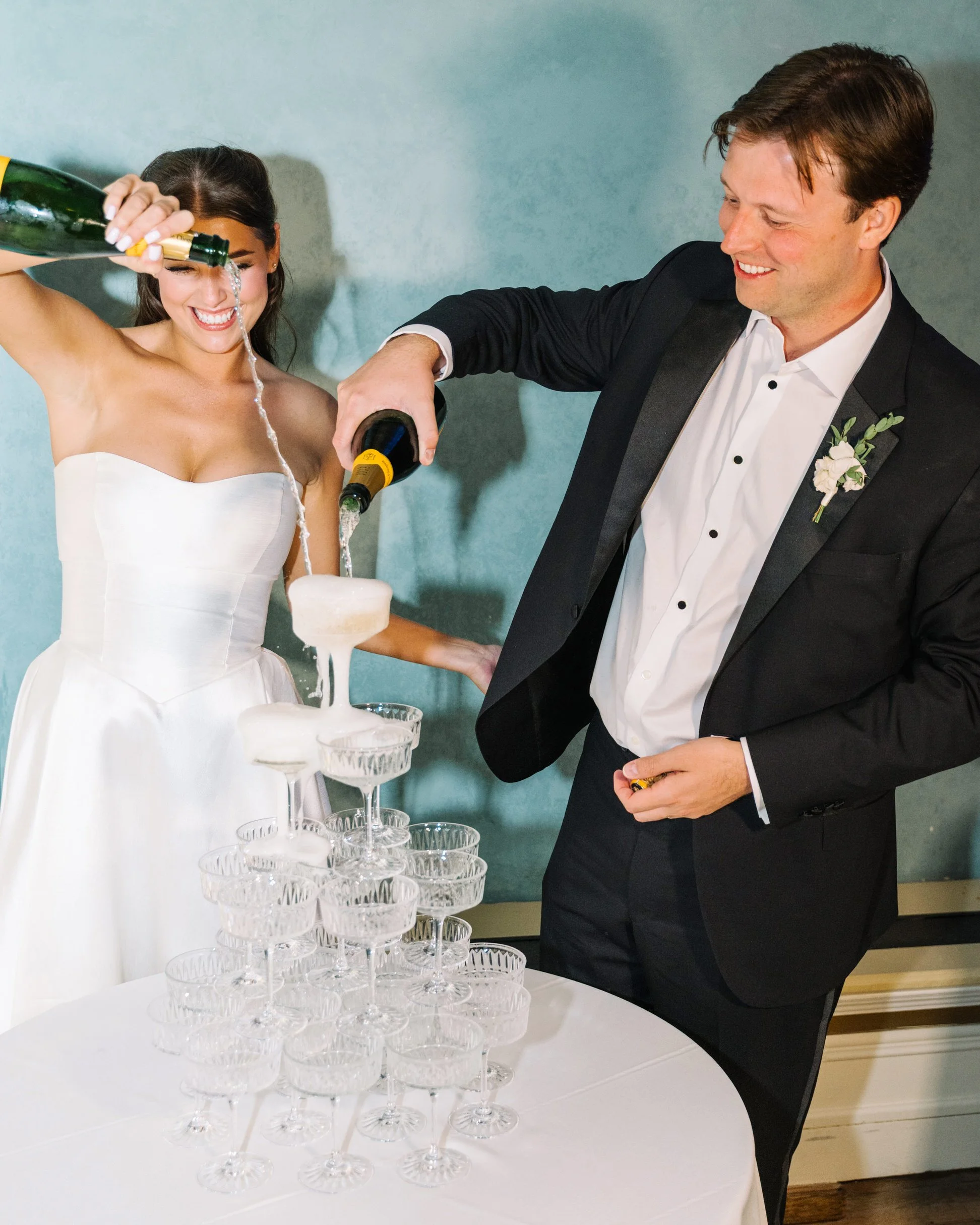 Bride and groom pouring champagne into champagne tower 