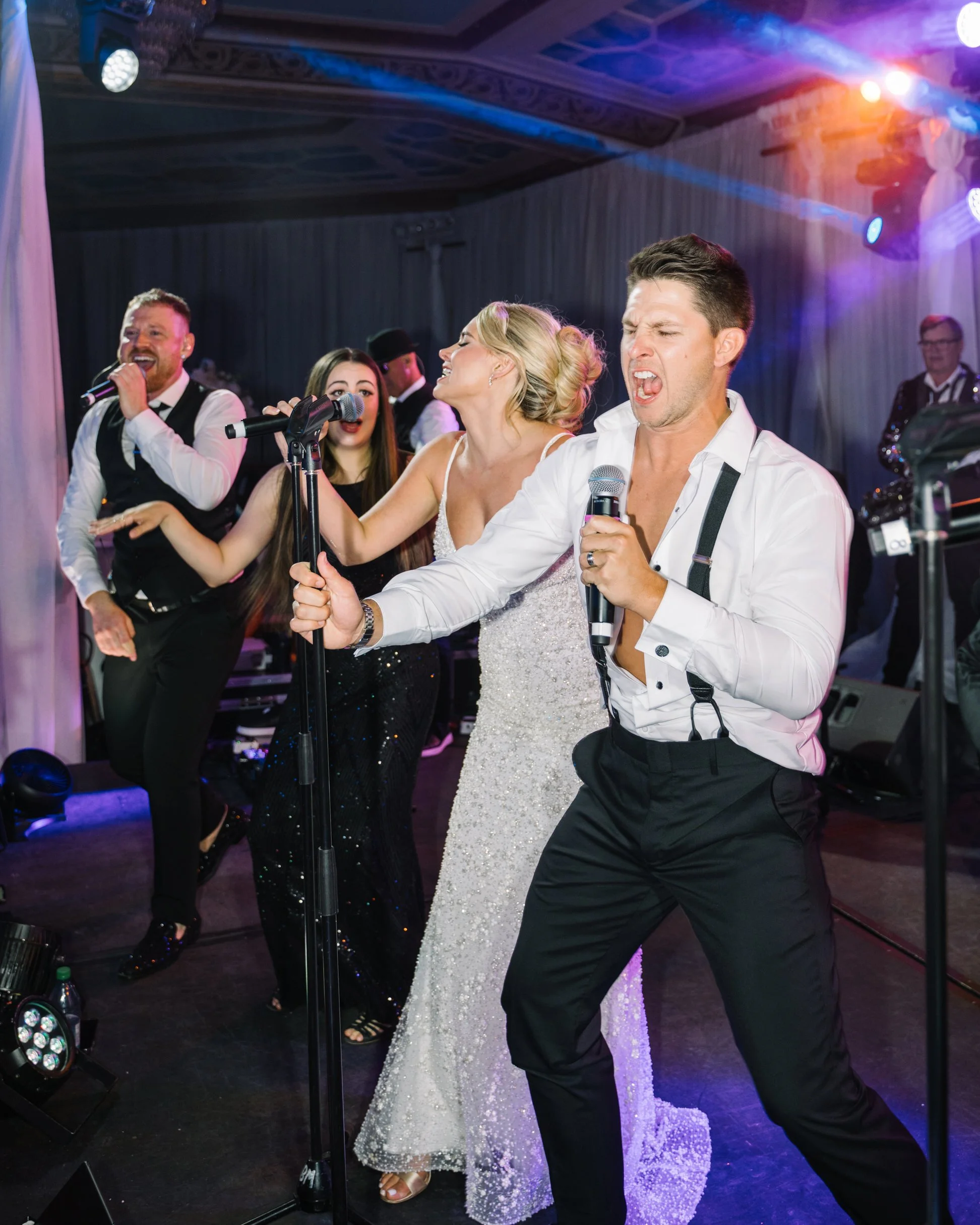 bride and groom on stage singing with the band 