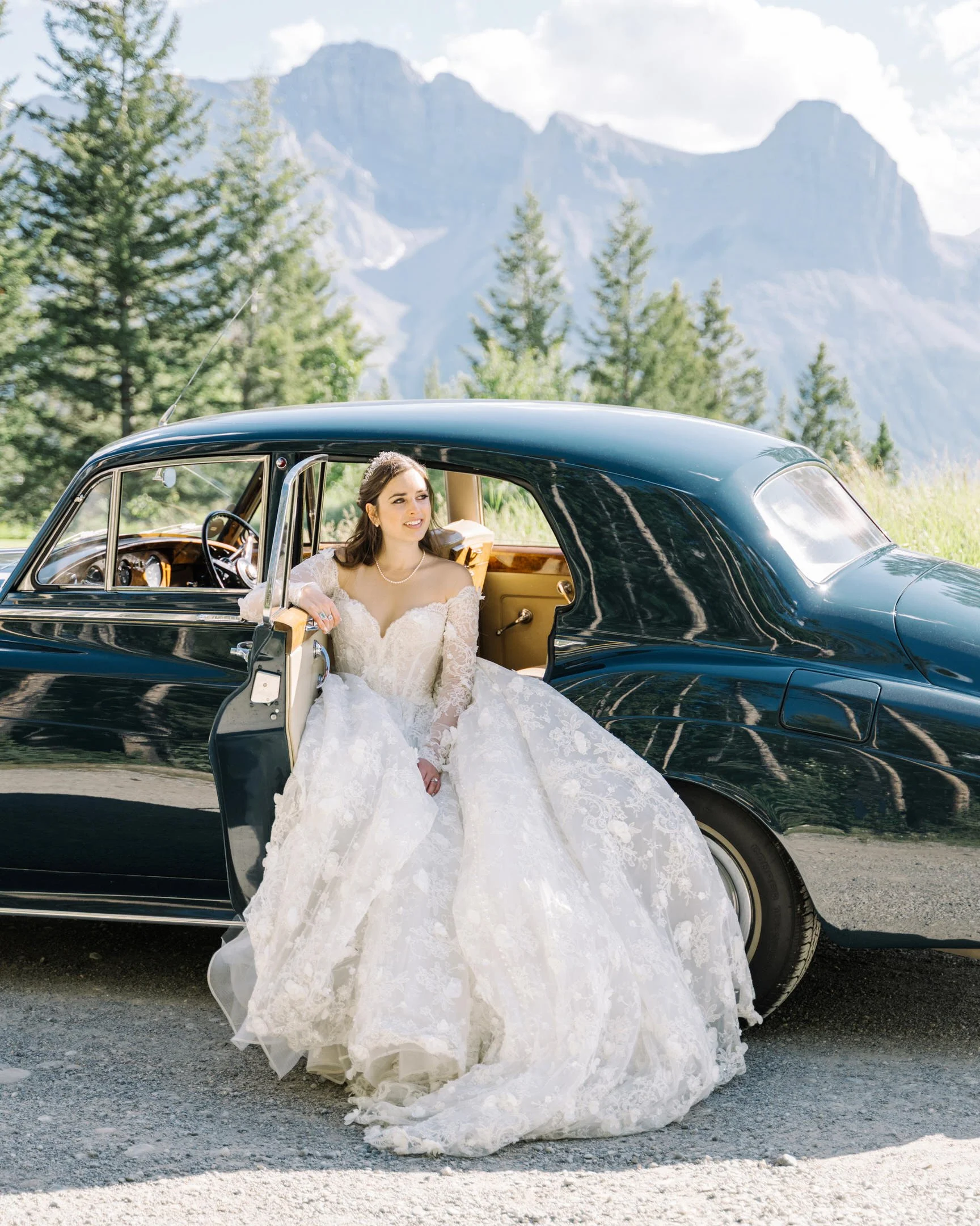 Bride with vintage blue car and mountain backdrop in Canmore