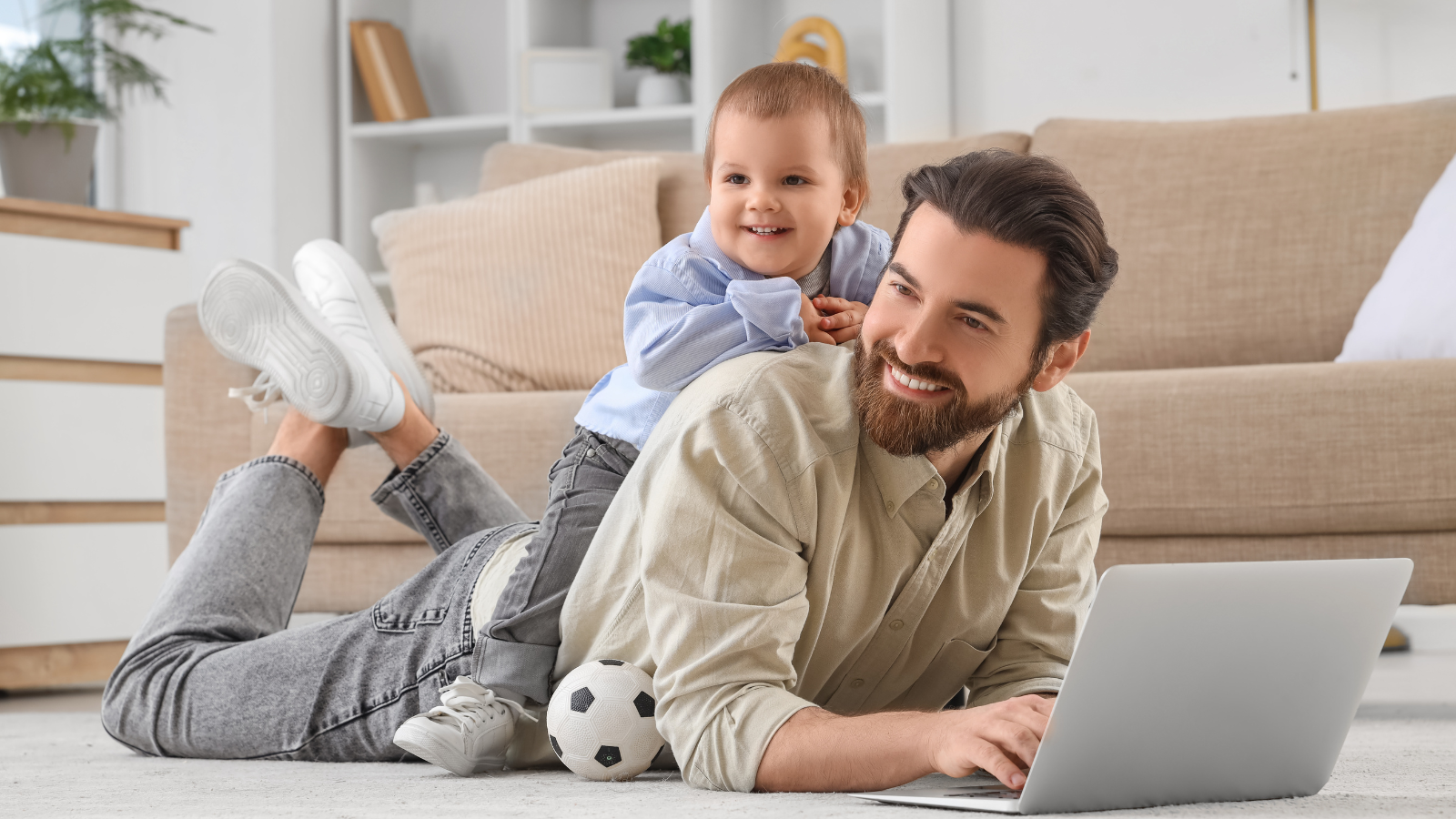 Father with baby & football at home sofa.png