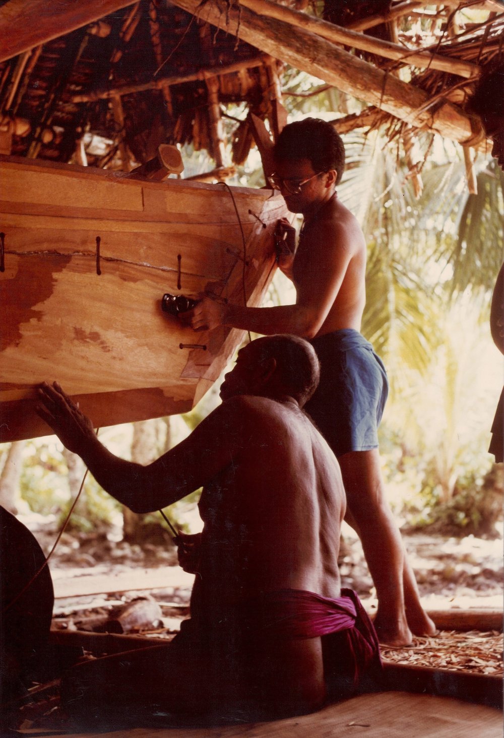  Master Navigator/Canoe Builder Tawa Tilimwar (left) and apprentice Gary Perez Guerrero of Yigo Village, Guahan, work on ‘Kefetek’ sailing canoe in Lepoput Canoe House, Polowat Atoll Relong Village, 1986. Photo by Rob Limtiaco © 