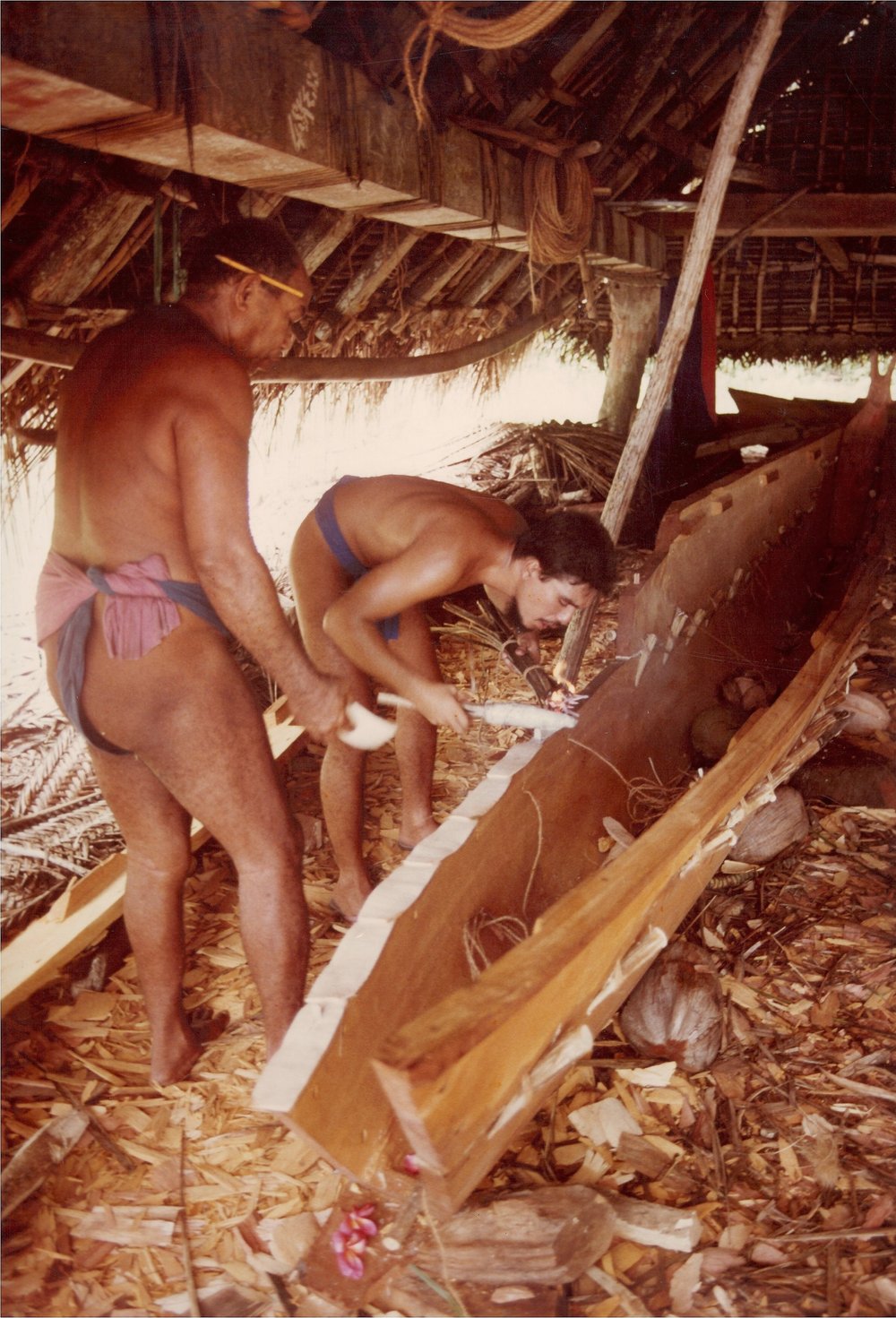  Master Navigator/Canoe Builder Tawa Tilimwar (left) and Rob Limtiaco (of Asan Village, Guahan) work on the sailing canoe ‘Kefetek’ in Lepoput Canoe House, Polowat Atoll Relong Village. They are ‘glue processing’ in preparation for lashing planks to 