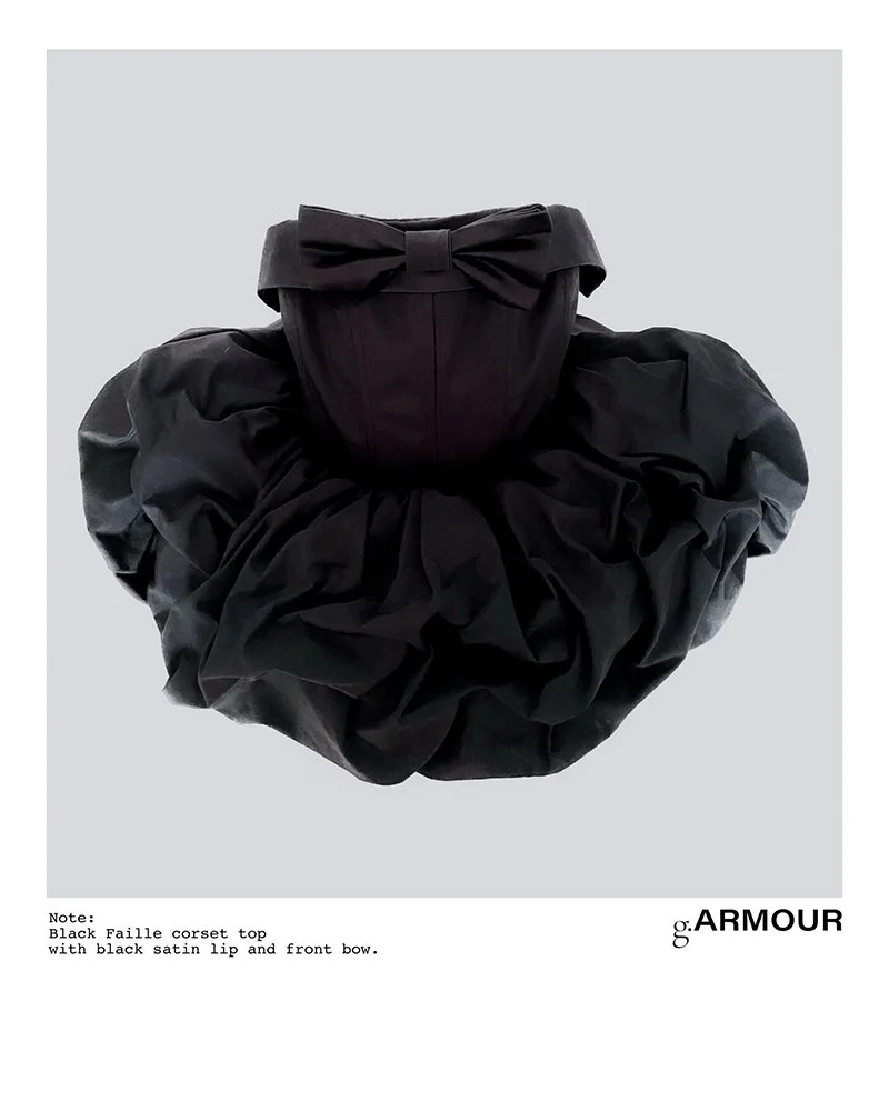 Black corset top with satin lip and front bow, paired with a voluminous black skirt, displayed on a gray background.
