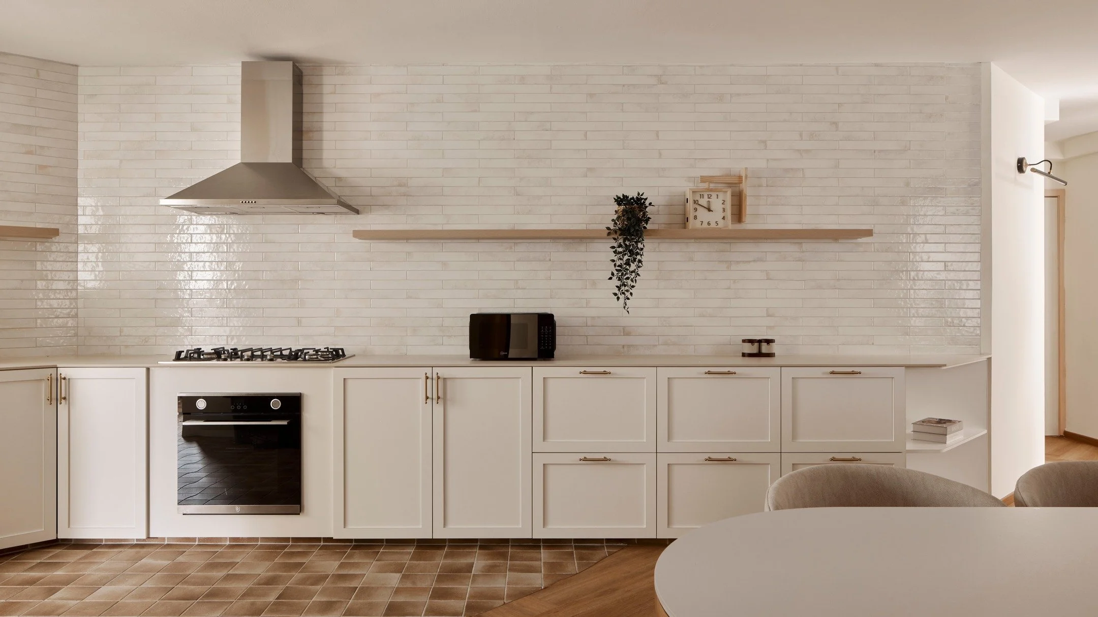 [Swipe right to see 'before' photo]

Removing the store room and keeping to a clean material palette has really paid off here.

The window is no longer obstructed and sunlight can now flood the entire space. White reflective subway wall tiles further