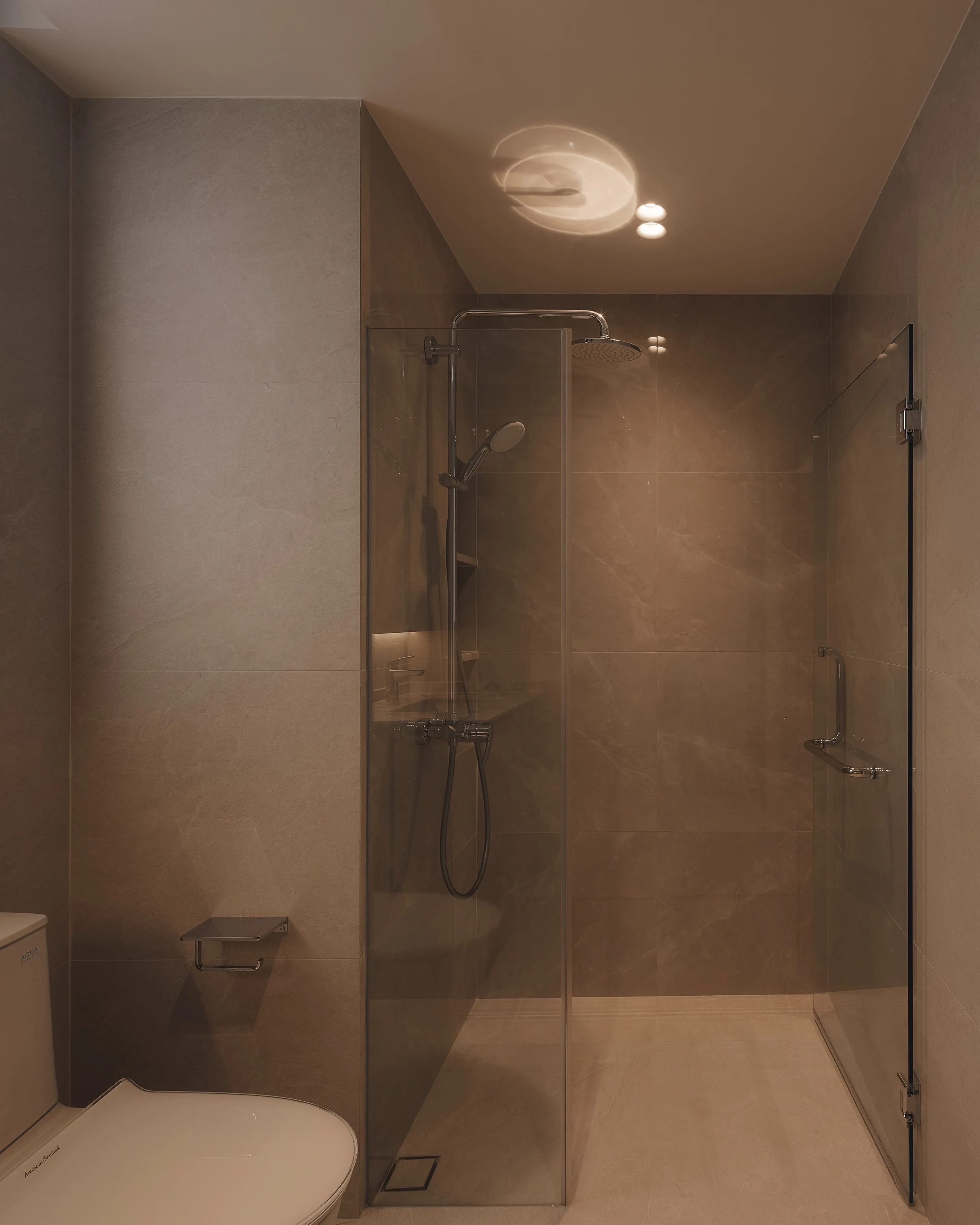 This bathroom is beige, yet interesting, through a mix of glossy tiles in the shower area, and matte tiles everywhere else. 

The reflection from the shower head on the ceiling was unexpected and very much welcomed 😊