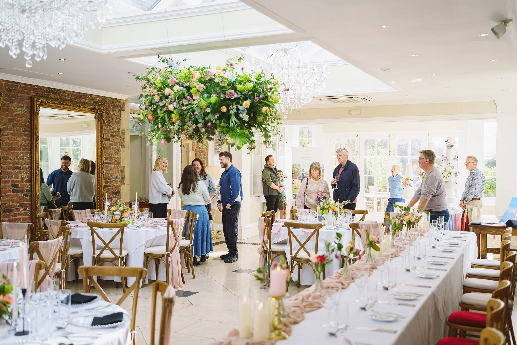 Image shows the Orangery at Goldsborough Hall, North Yorkshire set for a wedding with people looking around at a wedding open afternoon