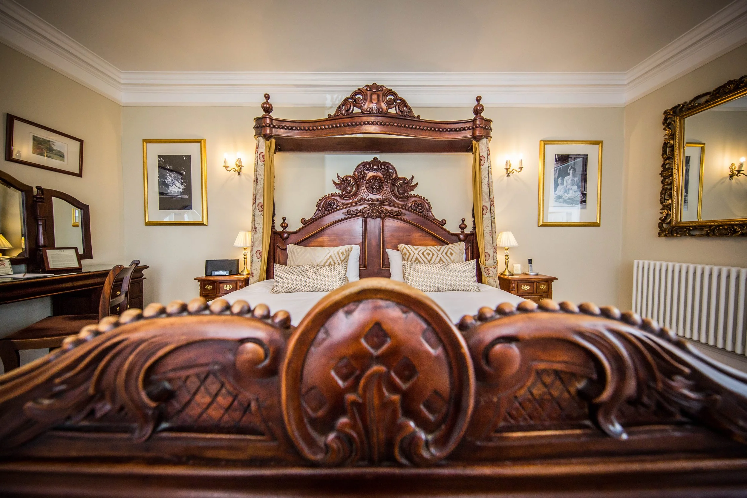 Image shows a half tester wooden bed in an elegant bedroom at Goldsborough Hall, North Yorkshire wedding venue