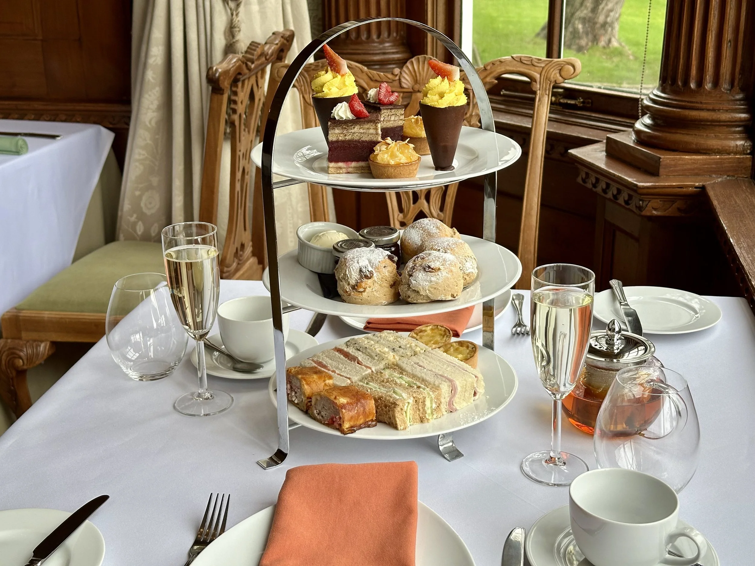 Afternoon tea on a three-tier stand, two glasses of champagne and table settings for two people