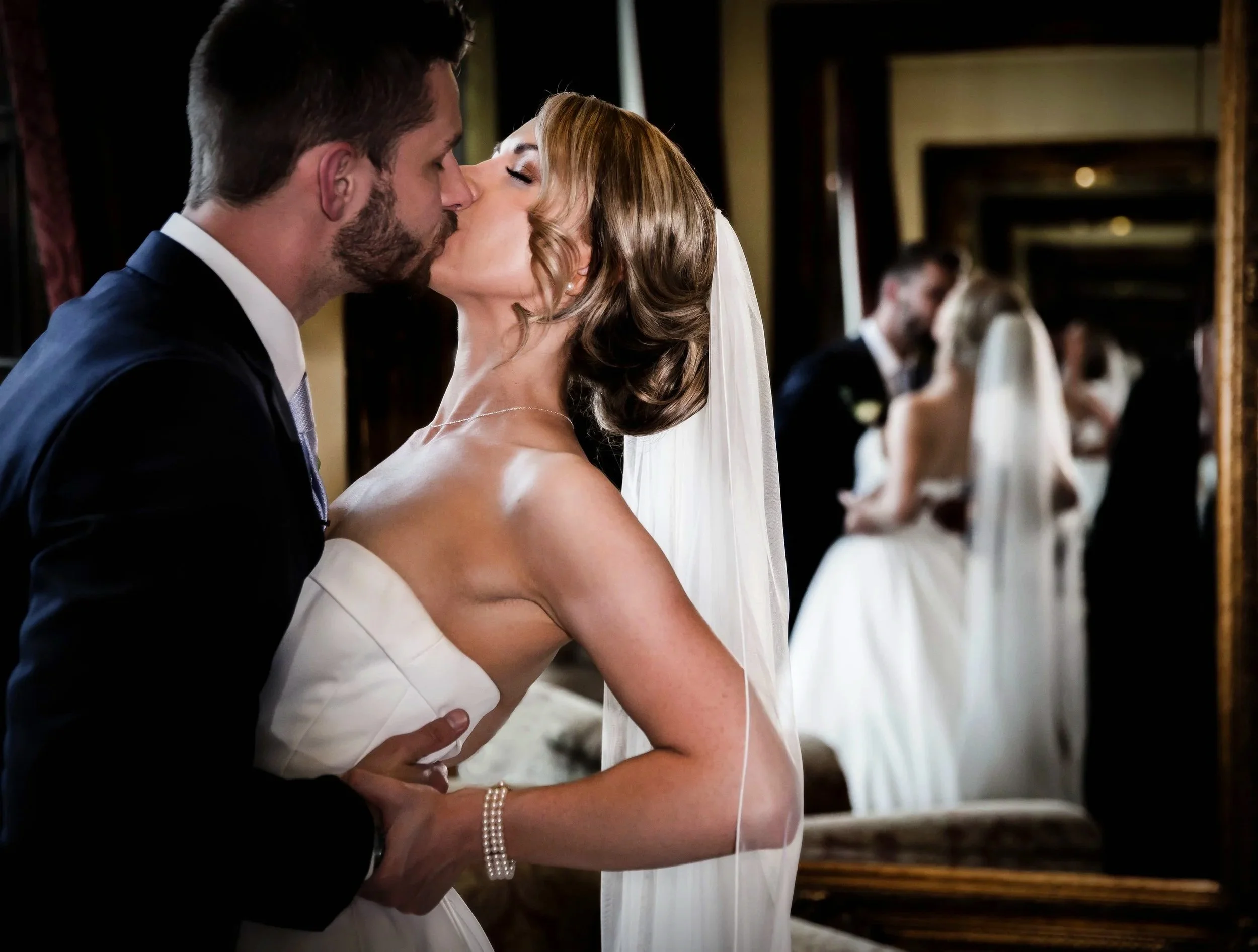 Wedding couple kissing on the stairs reflected in the mirror