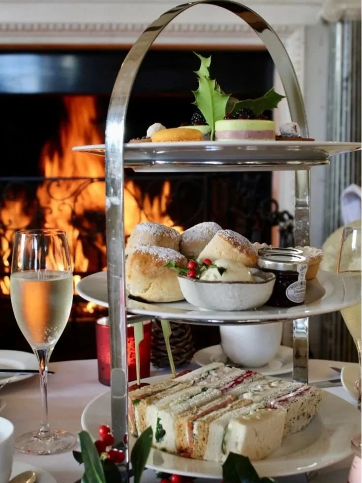 Close up of an afternoon tea stand with a roaring log fire behind